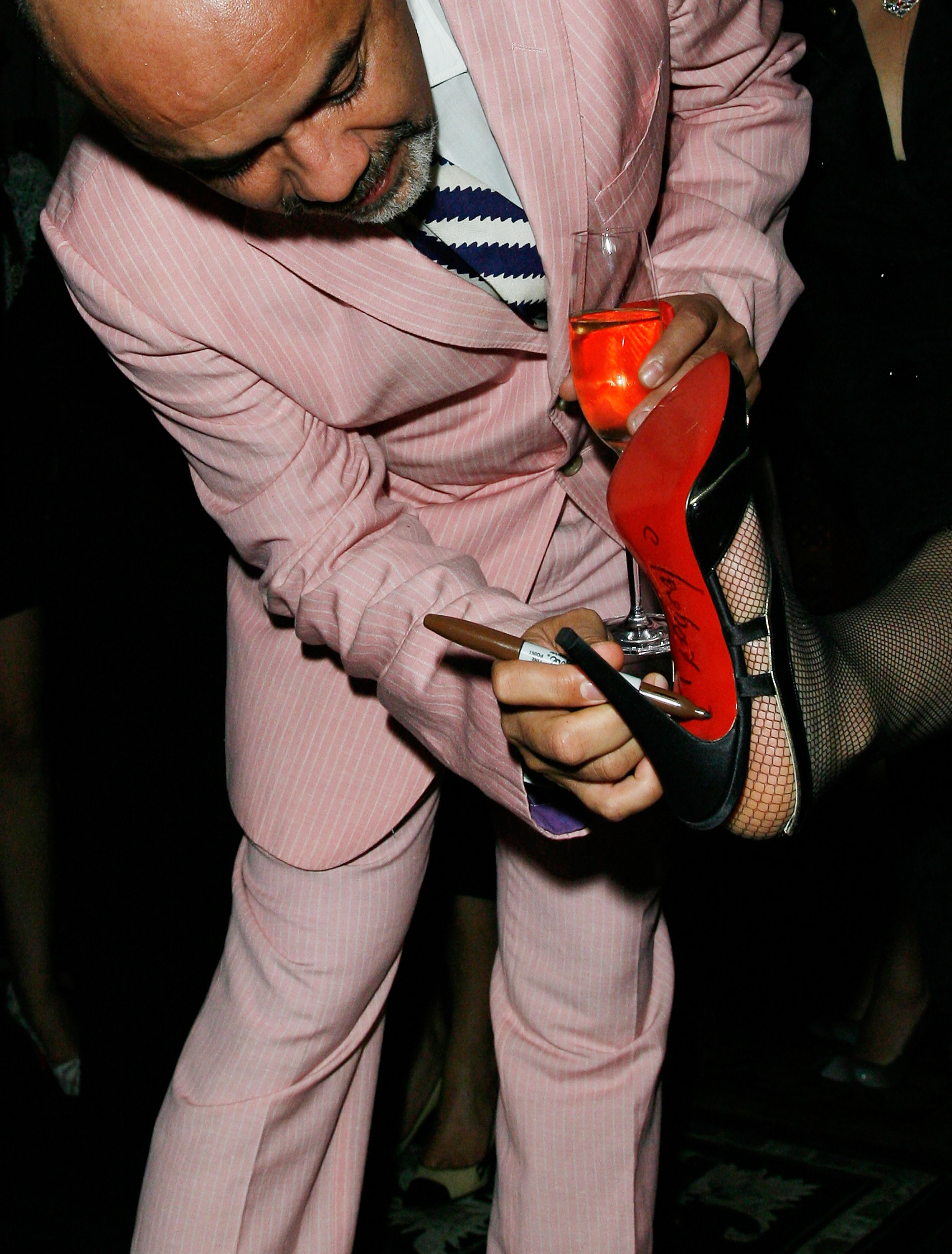 Designer Christian Louboutin signs Saks costumer Mandy Li's shoe at a cocktail party in 2007. Photo / Getty Images