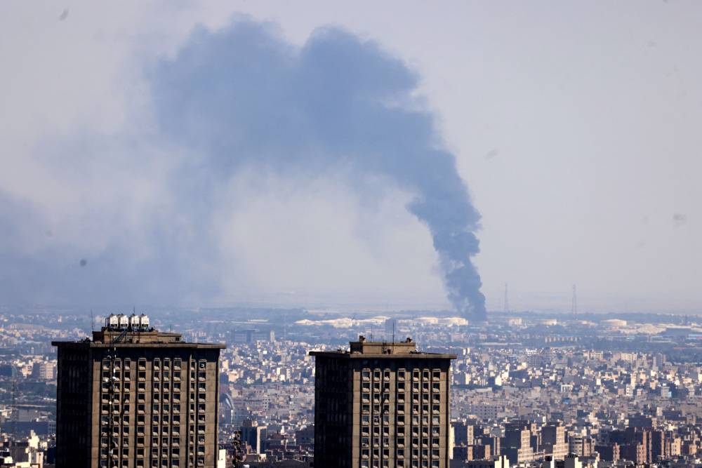 Smoke billows in the distance from an oil refinery following an Israeli strike on the Iranian capital Tehran. Photo / Atta Kenare, AFP