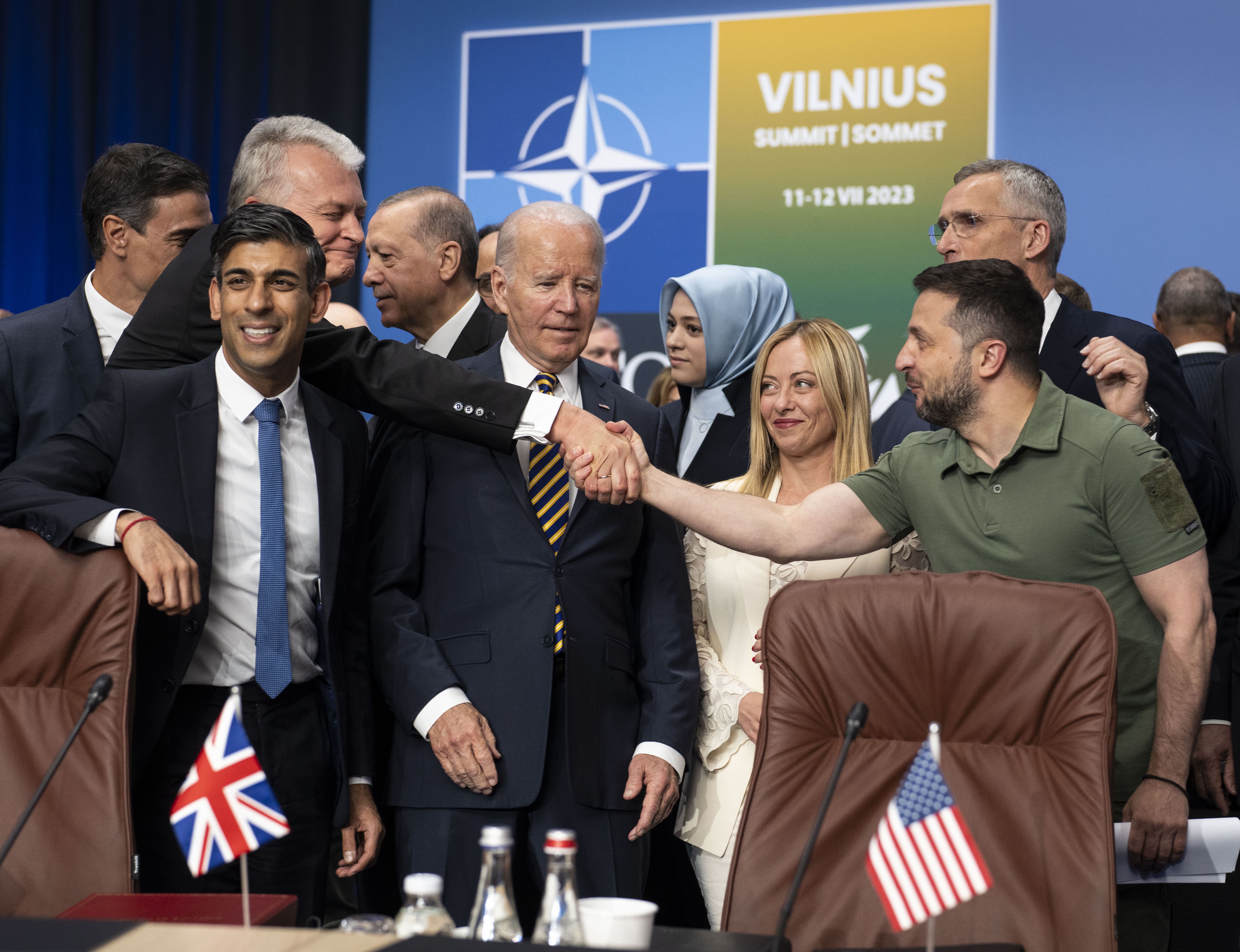 Ukrainian President Volodymyr Zelenskyy (right) reaches past US President Joe Biden to shake hands with Lithuanian President Gitanas Nauseda as they stand with other Nato members. Photo / AP