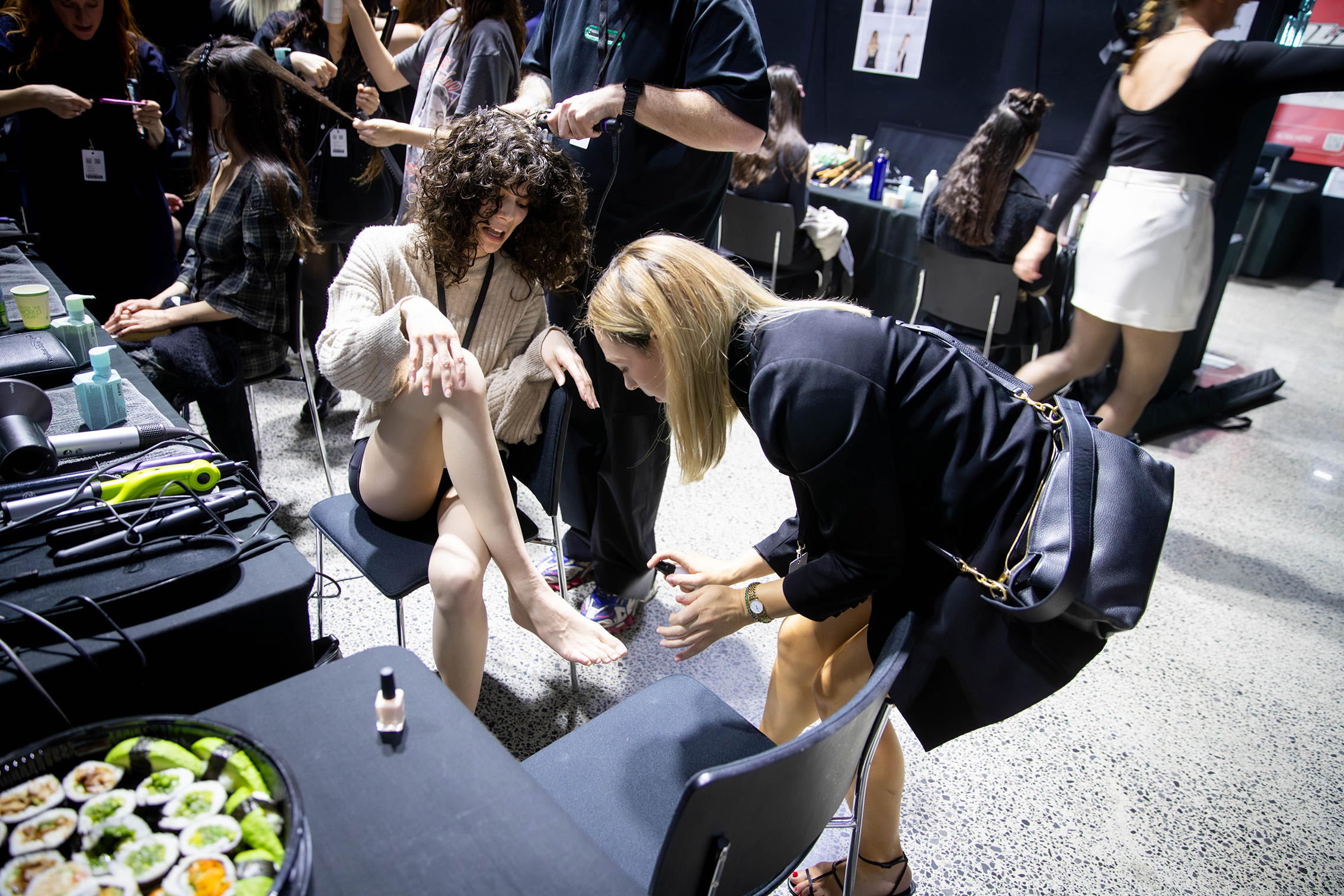 4.59pm: A pre-show toe nail paint — and a side of sushi — for the models walking in Juliette Hogan's runway show. Photo / Michael Craig