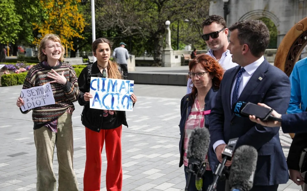 Aurora Garner-Randolph (left) and a friend protesting while Act leader David Seymour speaks to media. Photo / Nathan Mckinnon, RNZ
