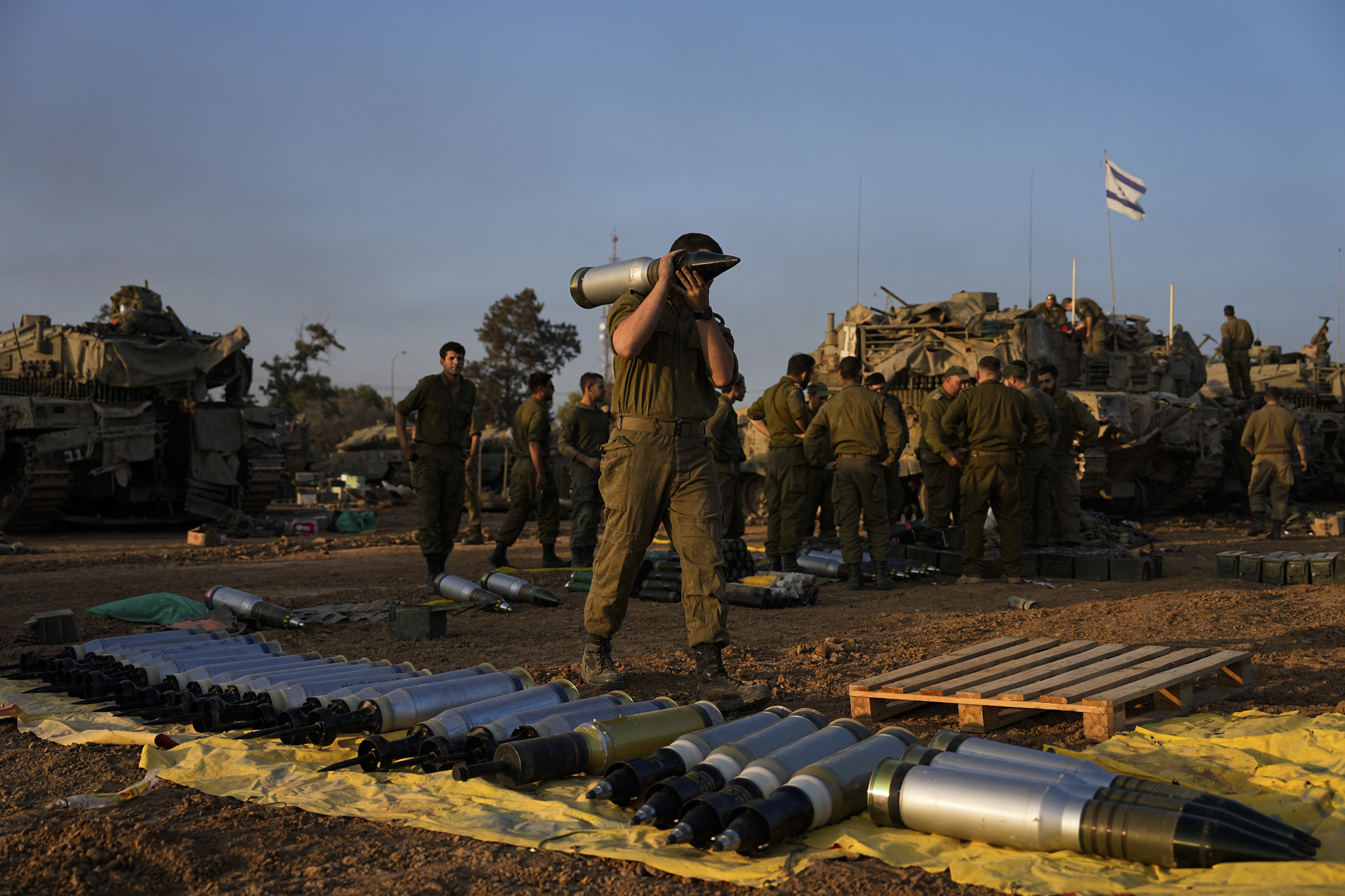 Israeli soldiers load shells onto a tank at a staging area in southern Israel near the border with Gaza. Photo / AP