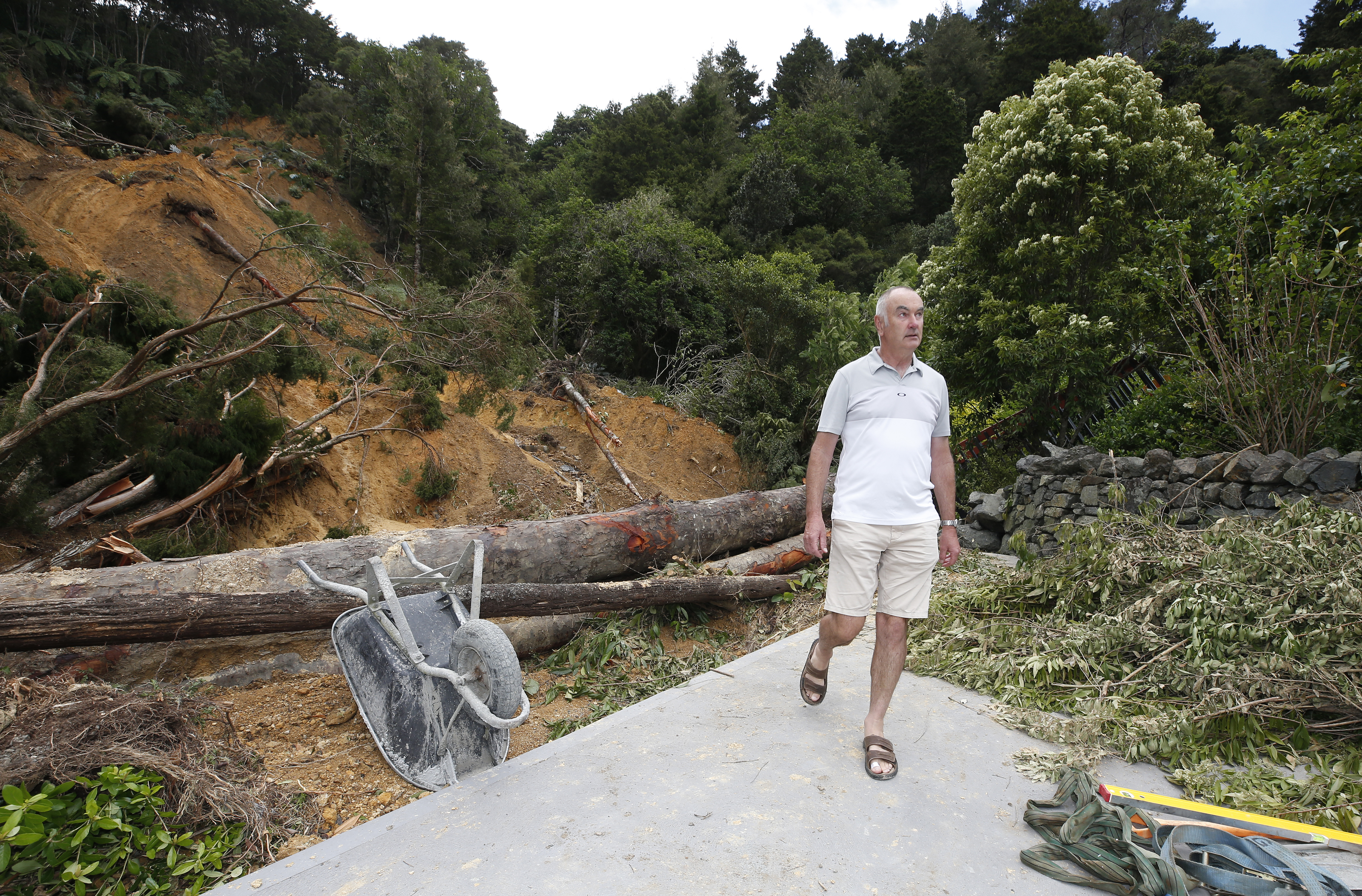 Garden Manager Guy Hessell is pictured in front of where the bridge connecting the gardens would usually sit. Underneath, the river is covered by mud. It's impossible to enter the gardens from its main entrance side now.  Photo / Michael Cunningham
