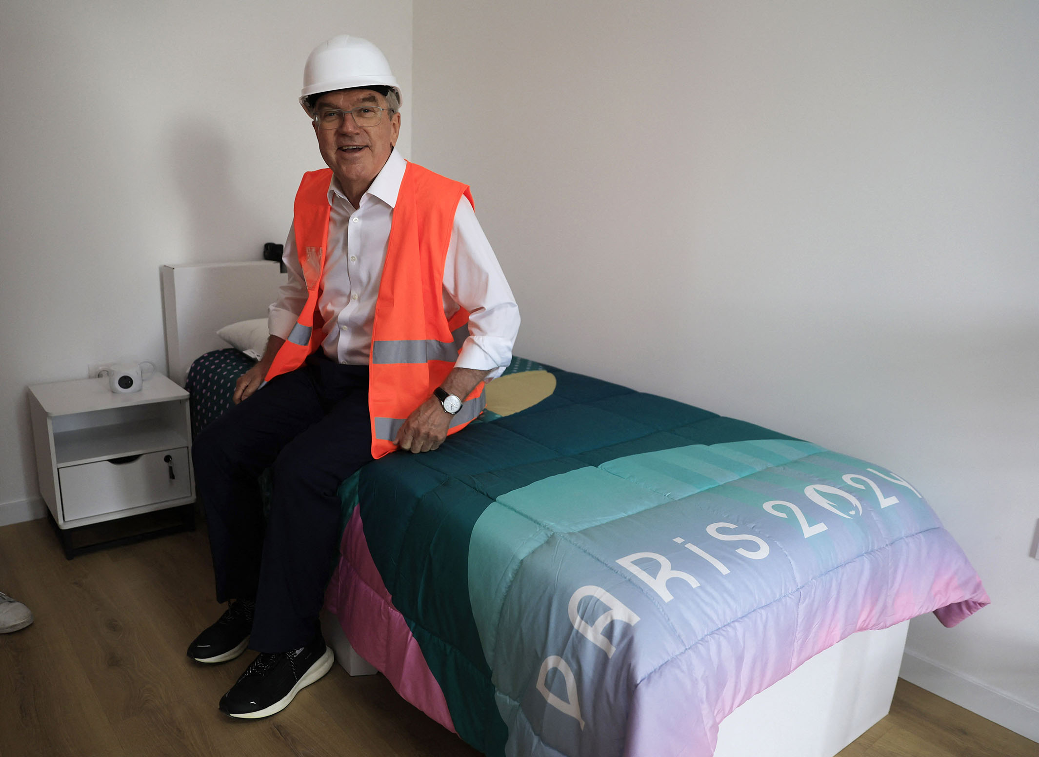 International Olympic Committee president Thomas Bach tests a cardboard bed in the Olympic Village. Photo / AP