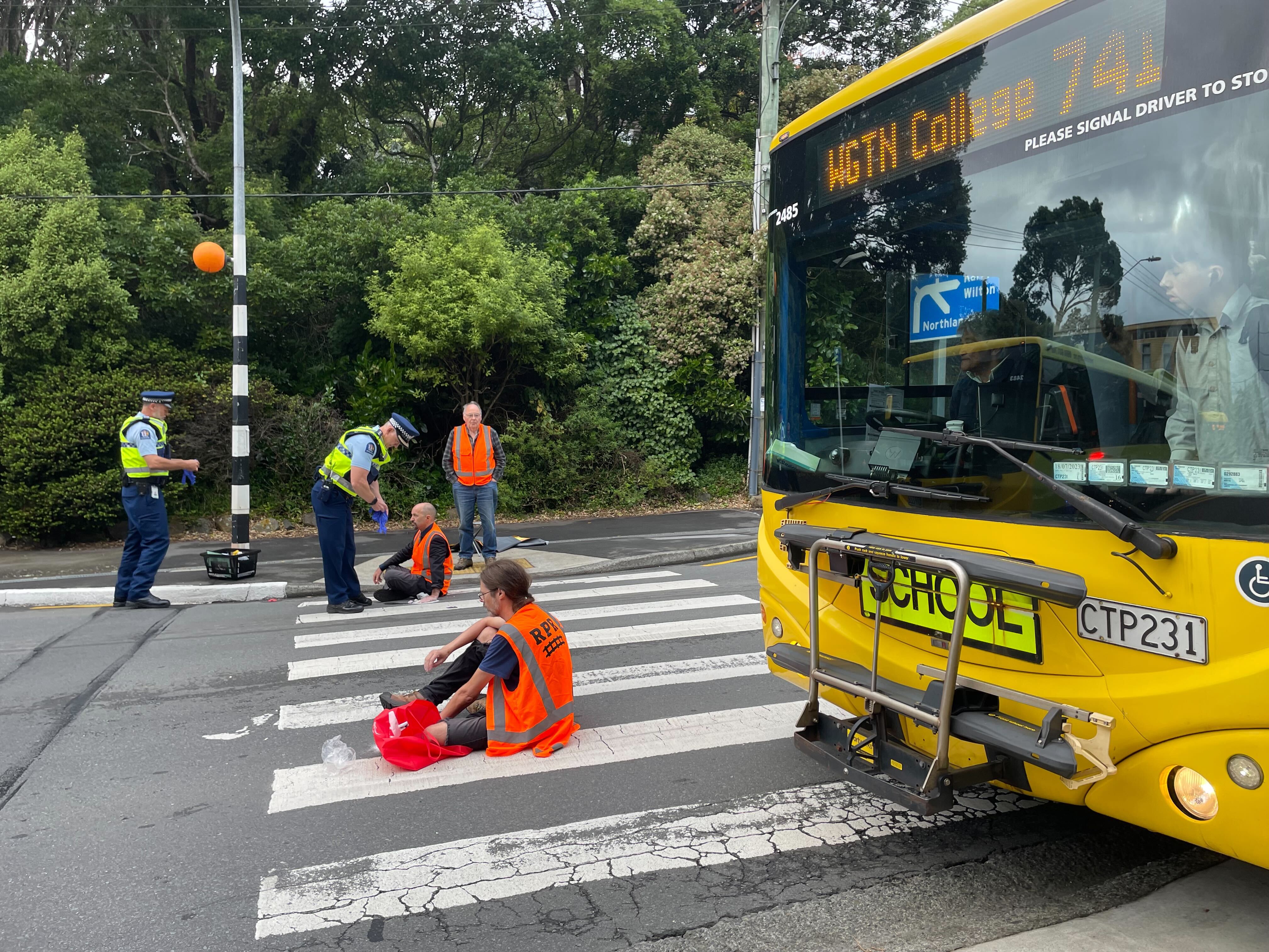 A school bus tried to edge past Restore Passenger Rail protesters on Glenmore Street, Karori. Photo / Azaria Howell