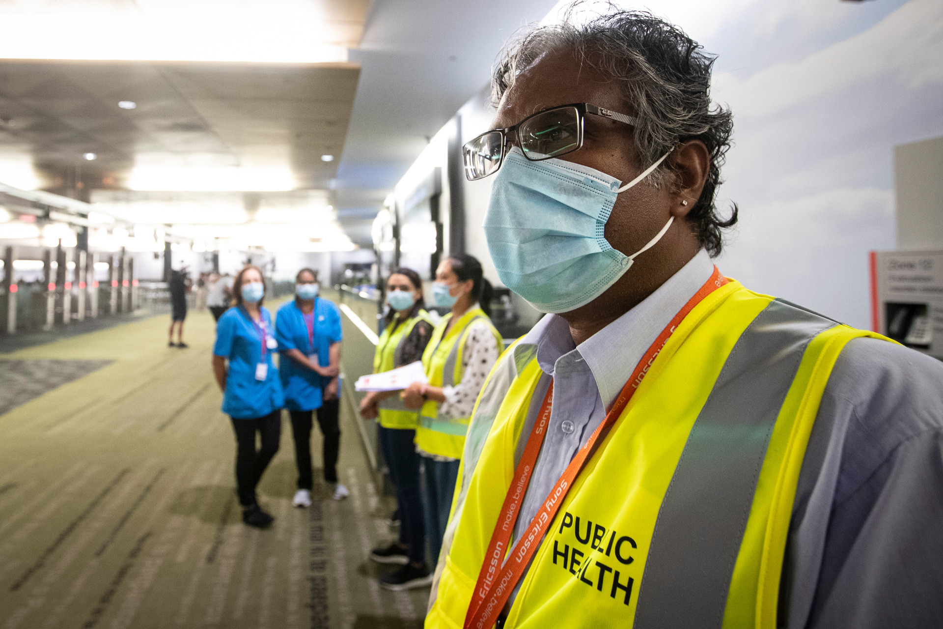 Masked health officials in the customs hall at Auckland International Airport in March. Photo / Jason Oxenham