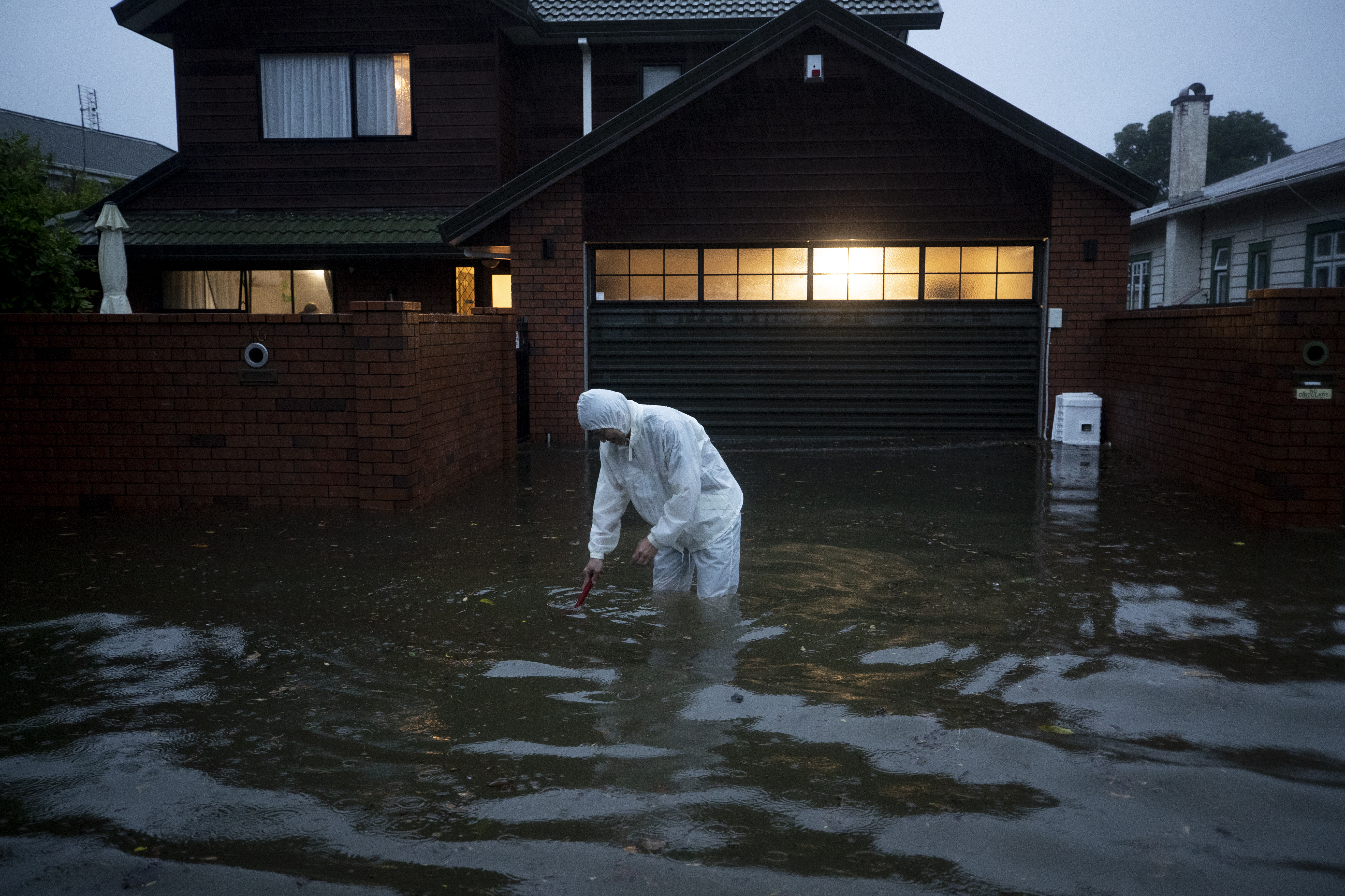 A man tries to clear the drain outside his house in Greenlane during the worst flooding the Auckland region has ever experienced. Photo / Dean Purcell