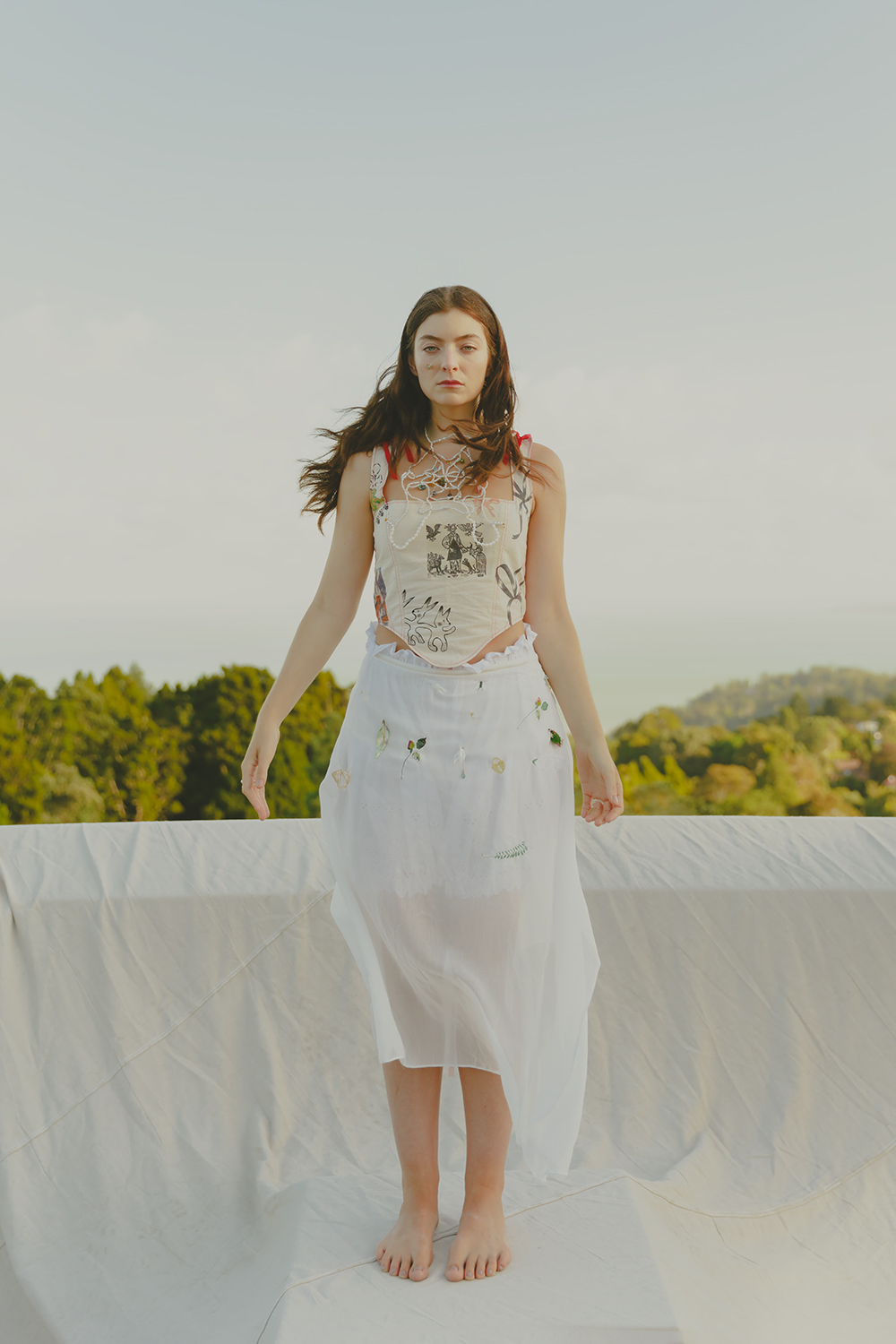 A sunset overlooking Titirangi’s lush green natives provides a moment for respite and reflection. Sleeping Profit, the slow fashion project based in Otepoti, is created by Siara Chicane and aims to invoke a sense of playfulness and fantasy in everyday dressing. This printed corset, $222, is matched with a wrap skirt, knickerbockers and neckpiece (all POA) by fellow emerging designer Laura Graham. Photographer / Hohua Ropate Kurene