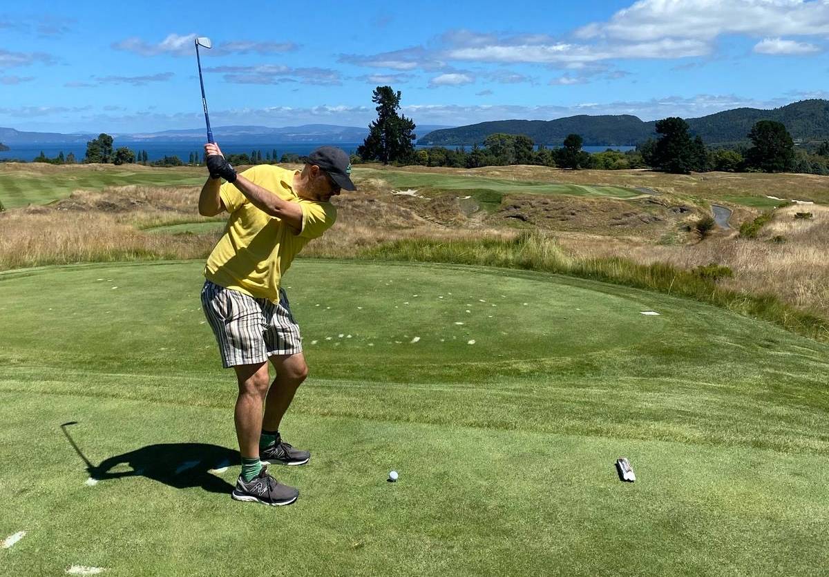 Teeing up on the par-three 17th at The Kinloch Club with Lake Taupō in the background.