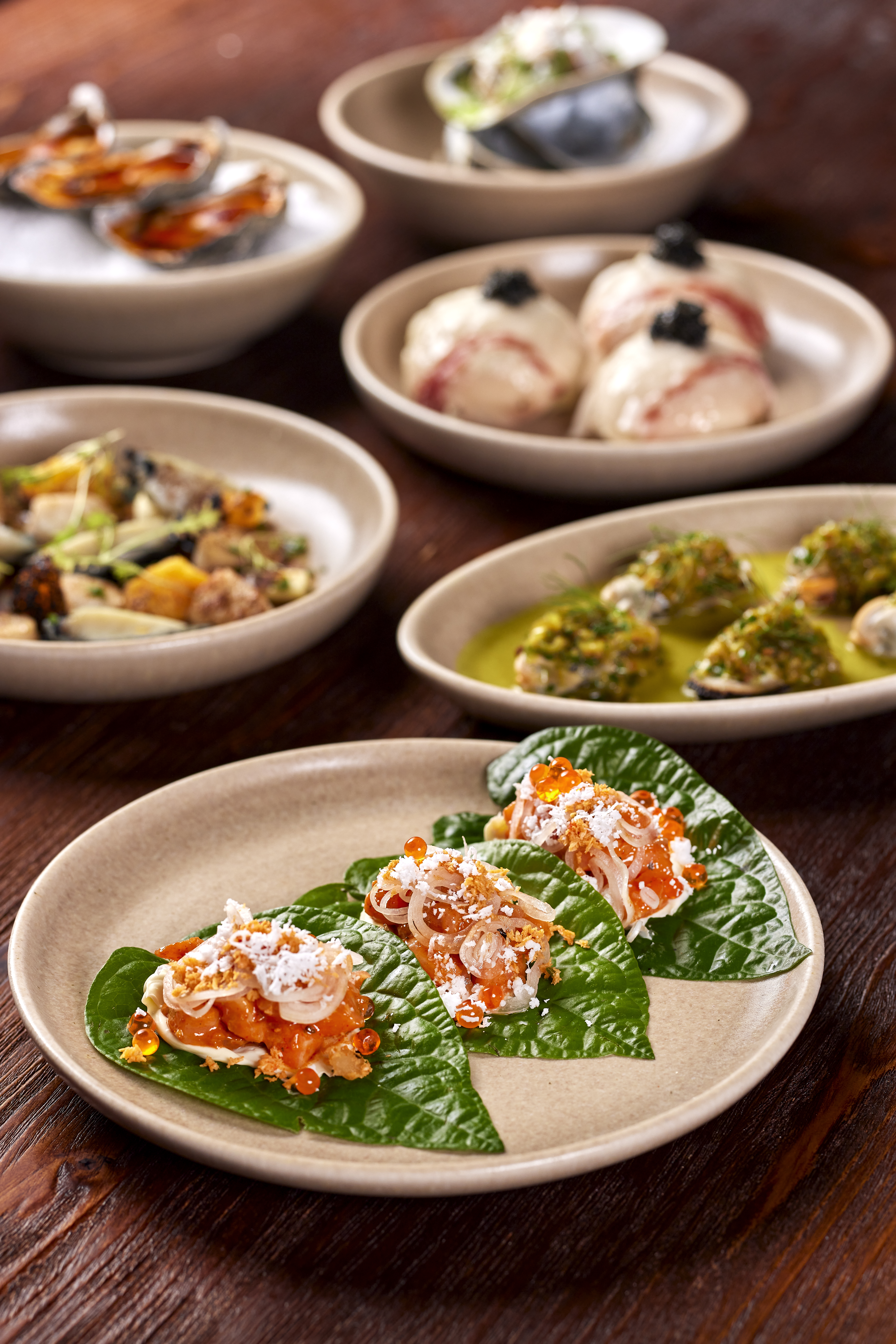Metita dishes including King salmon on a betel leaf with mango pickle and roe; corn beef bun with lardo and caviar.