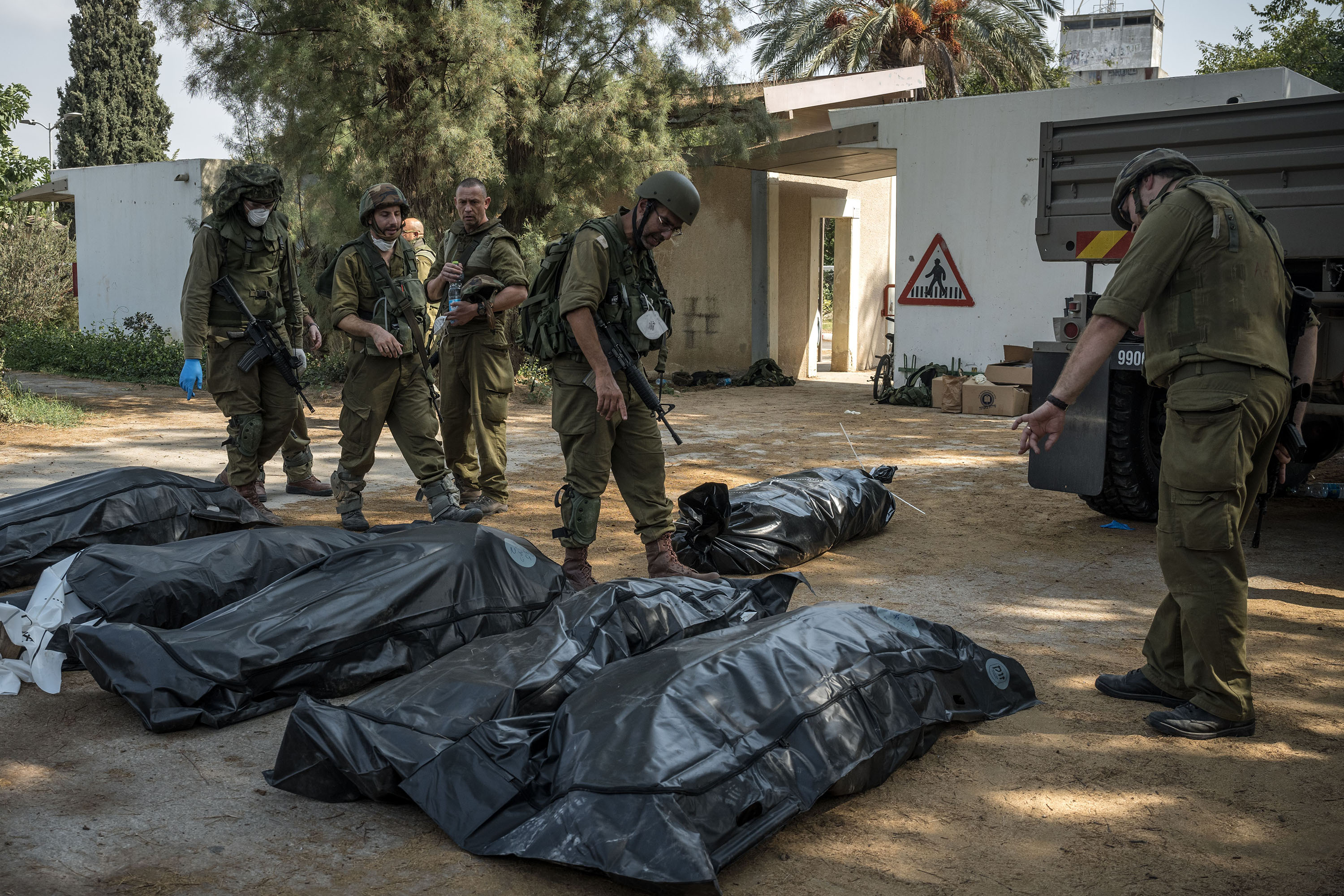 Israeli soldiers inspecting the bodies of people killed in the village of Kfar Azza, Israel. Photo / Sergey Ponomarev, The New York Times