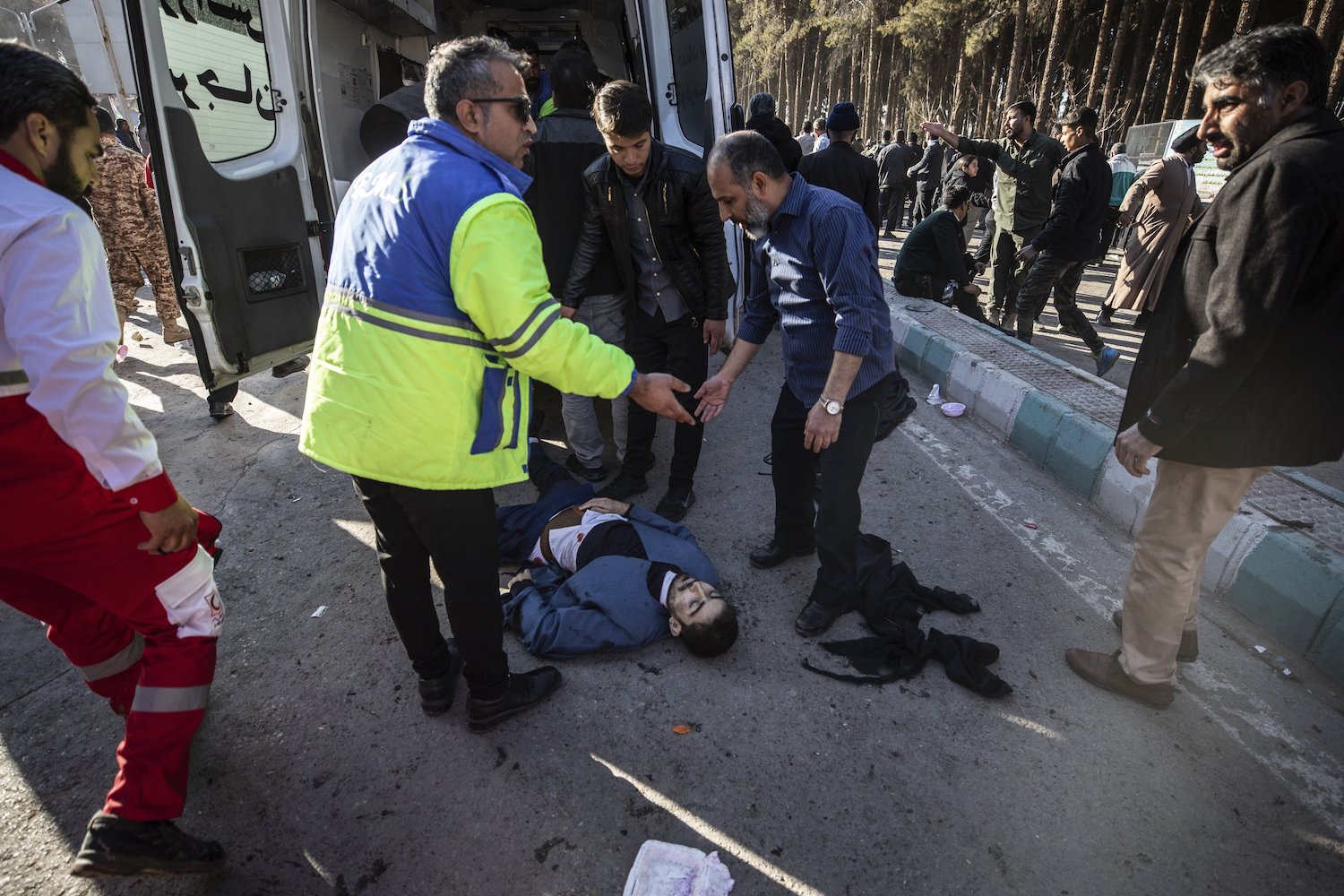 People stay next to an injured man after an explosion in Kerman. Photo / AP