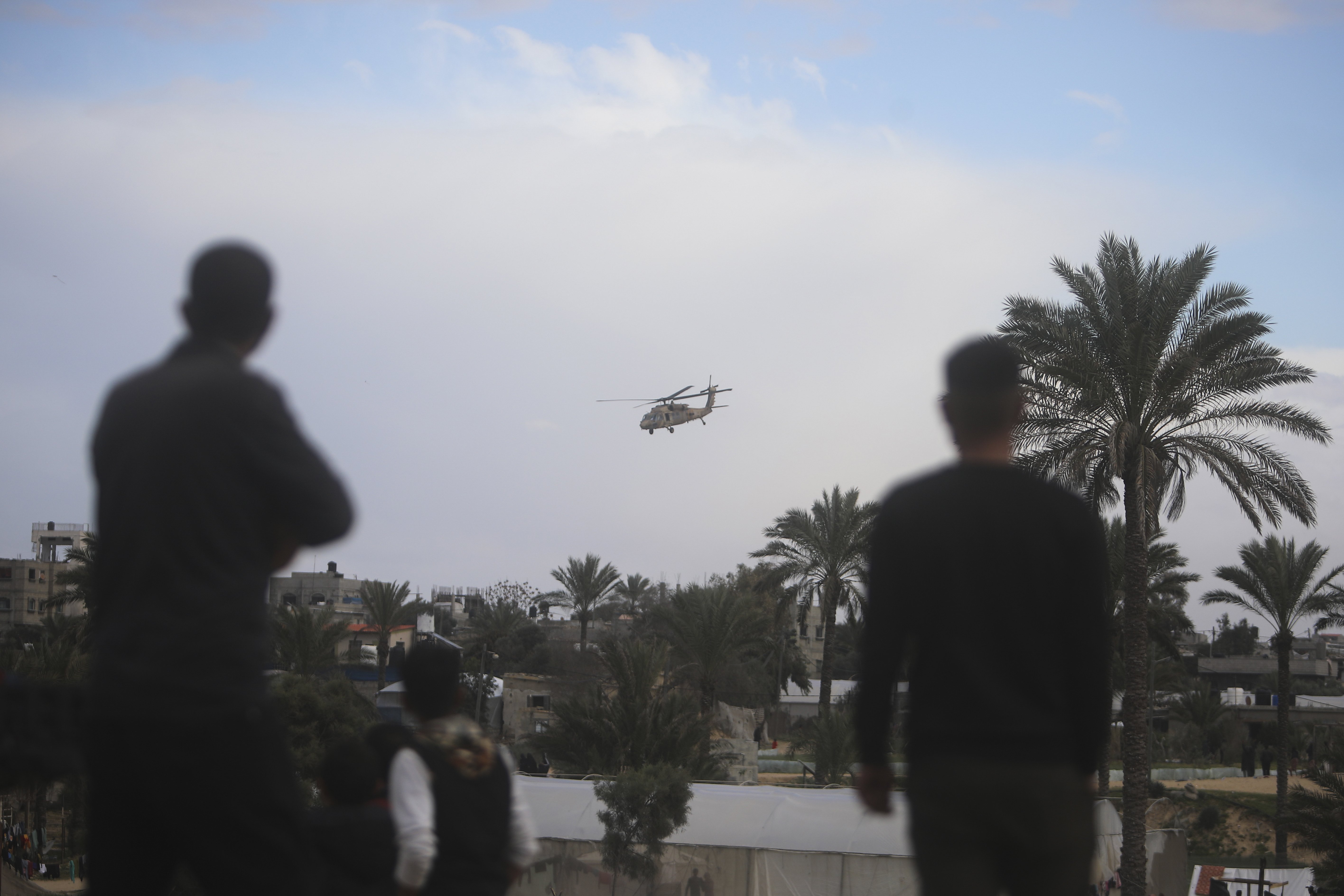 Palestinians watch an Israeli helicopter fly over Khan Younis, Gaza Strip, Thursday, Feb. 15, 2024. (AP Photo/Mohammed Dahman)�