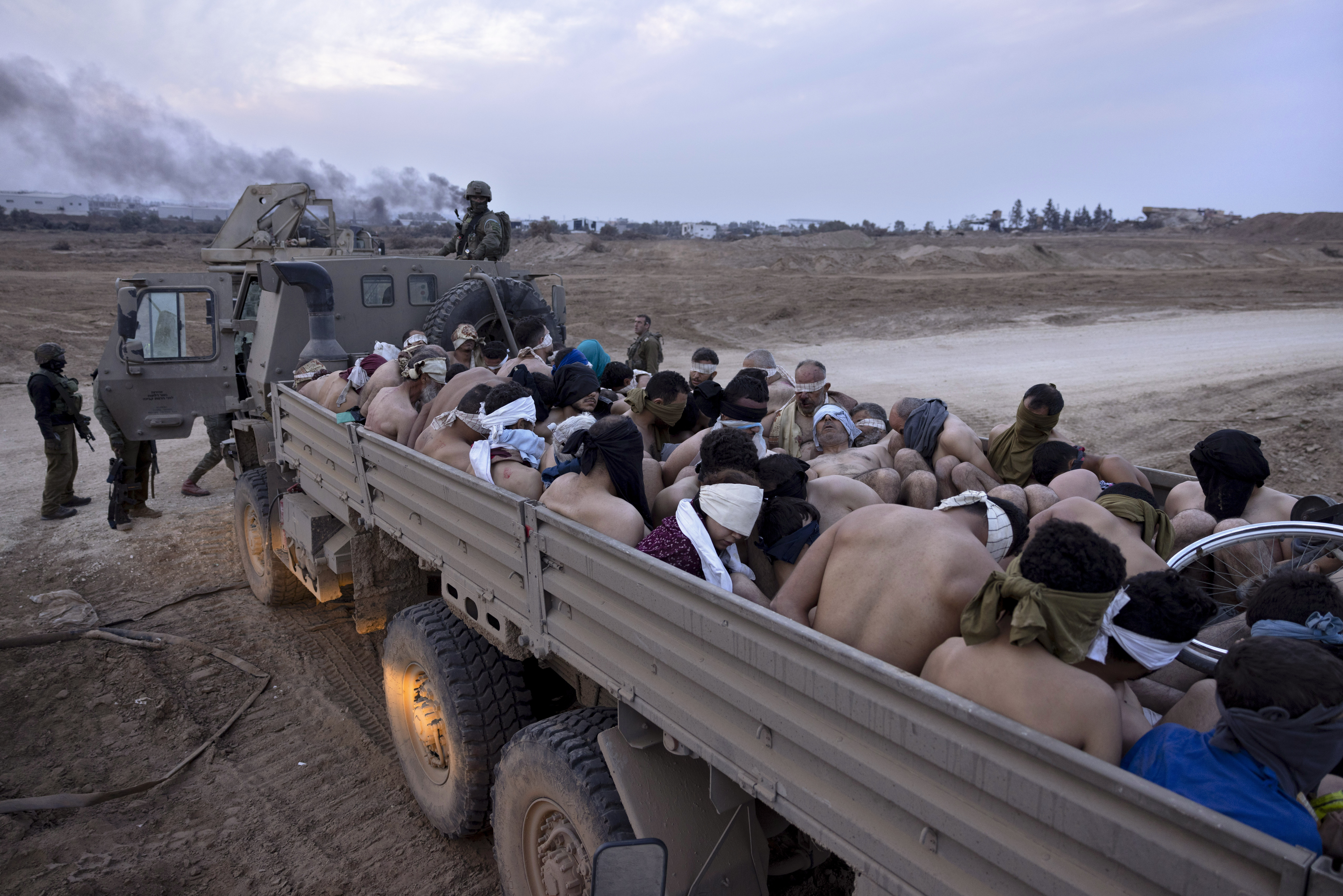 Israeli soldiers stand by a truck packed with bound and blindfolded Palestinian detainees, in Gaza. Photo / AP