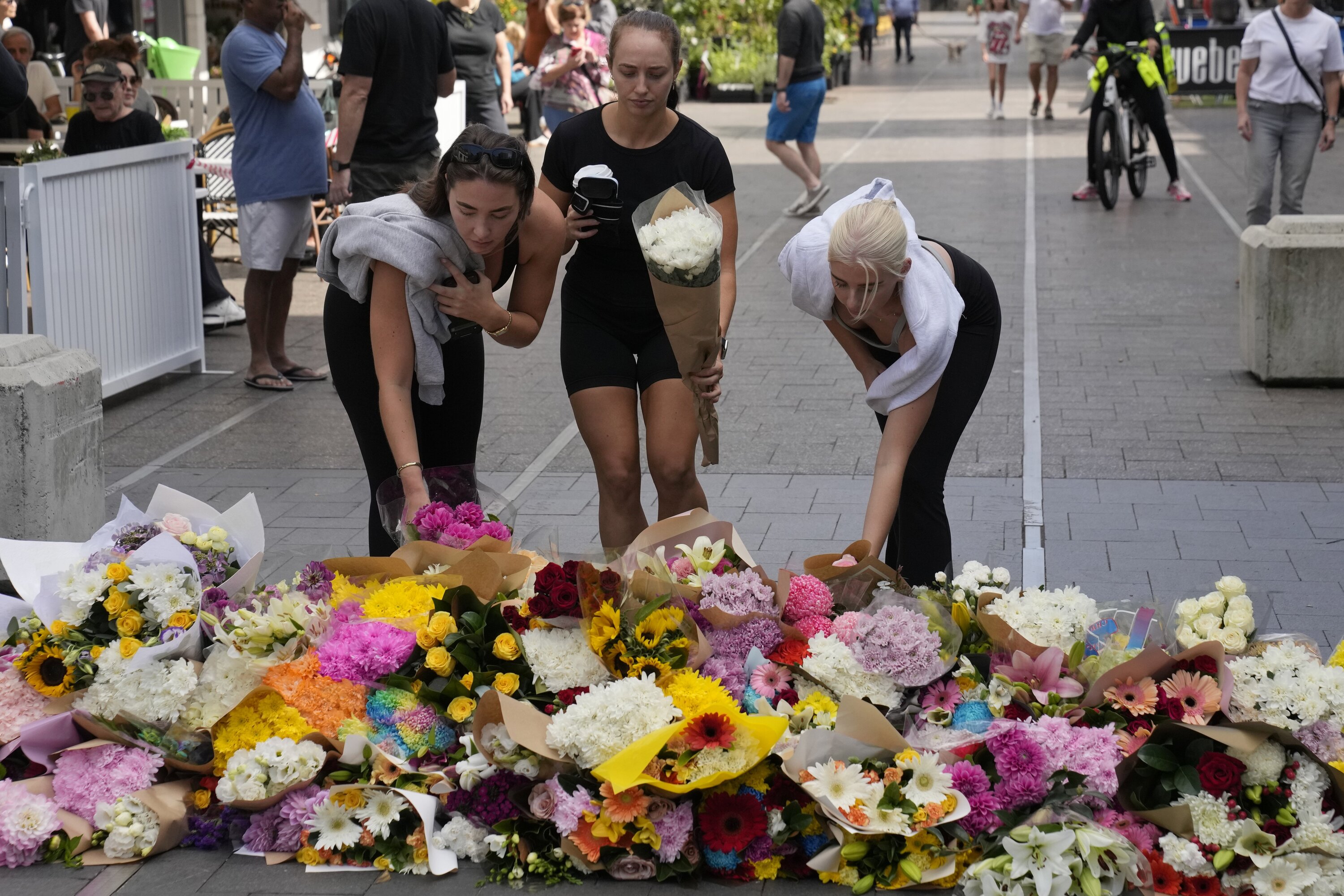 Three women place flowers as a tribute near a crime scene at Bondi Junction in Sydney on April 14, 2024, after five women and one man were stabbed to death at a Westfield shopping centre. Photo / AP