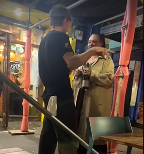 Mayor Tory Whanau holding a bottle of wine, in discussion with a waiter outside The Old Quarter on Friday.
