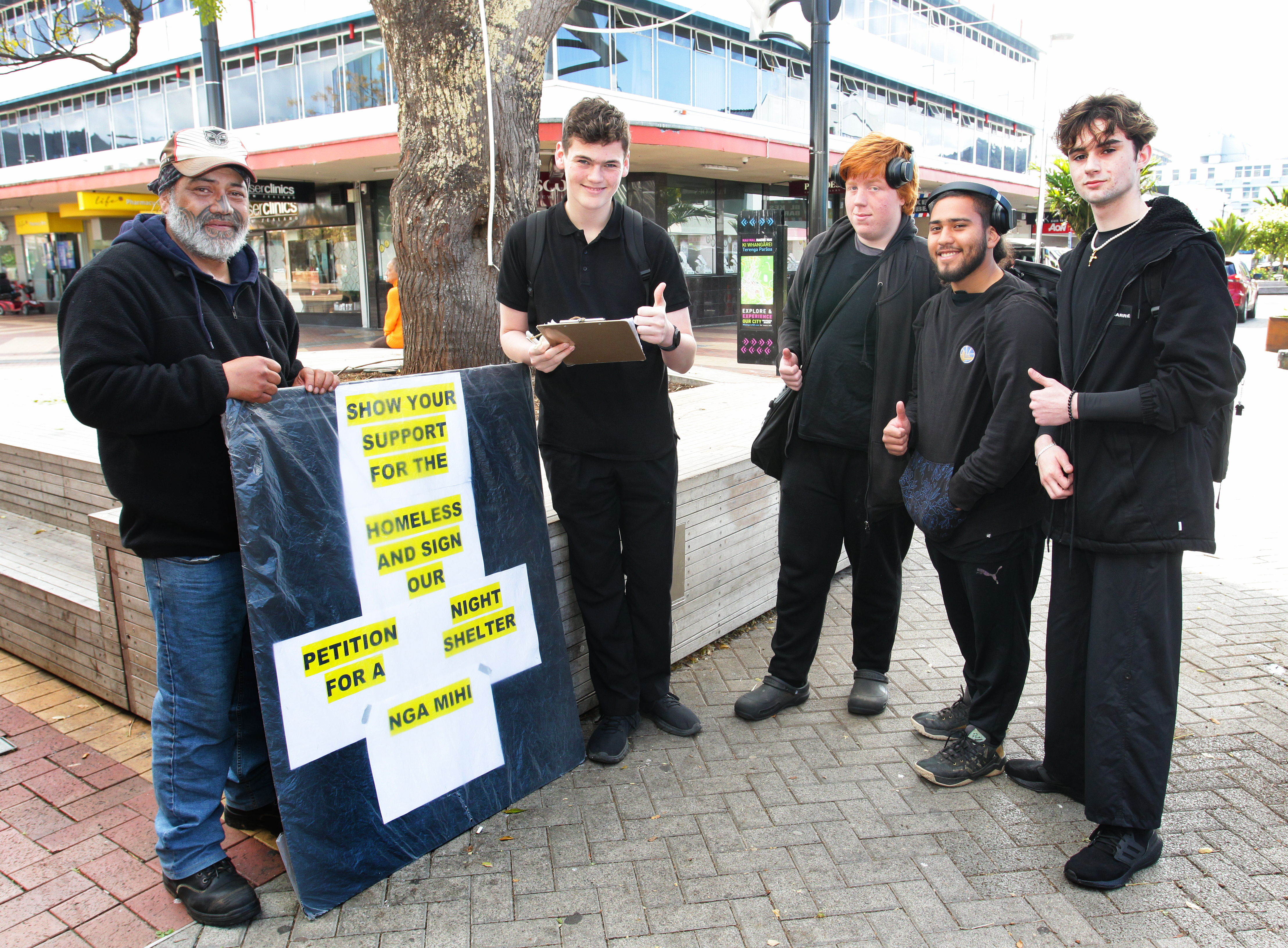 Whangarei Boys' High School students Lauchlan Marvin, Alex Wyatt, Cayle Rivas-Reti and Layton Koning sign Jason Poutai's petition calling for a permanent night shelter in Whangārei. Photo / Tania Whyte