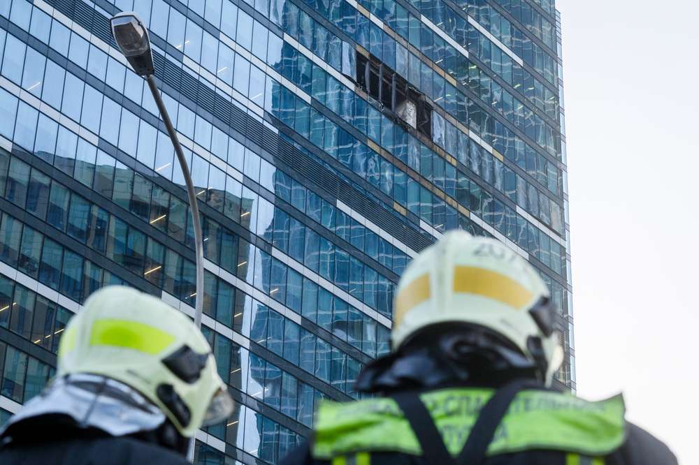 Firefighters stand next to a damaged building in the 