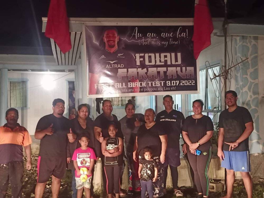 Folau Fakatava's family in Tonga at his parents' home with a banner celebrating his first All Blacks match. Photo / Supplied