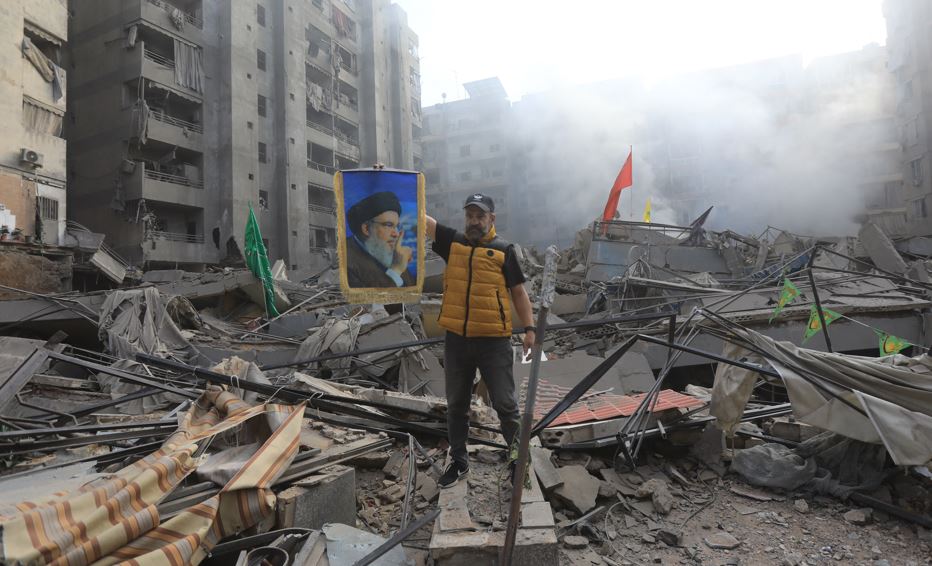 A man with a portrait of Hezbollah's slain leader Hassan Nasrallah stands amid the rubble of a building, flattened in an Israeli airstrike that targeted the Mreijeh district of Beirut’s southern suburbs. Photo / AFP