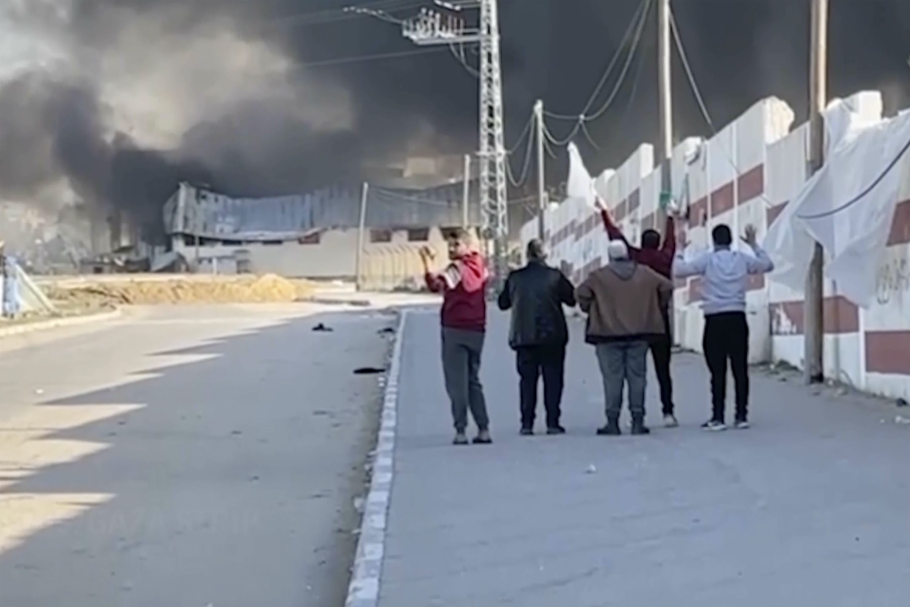 This image made from ITV News video shows a group of five men walking down a street west of the southern city of Khan Younis in Gaza while they hold their hands in the air and one waves a white flag. Photo / AP