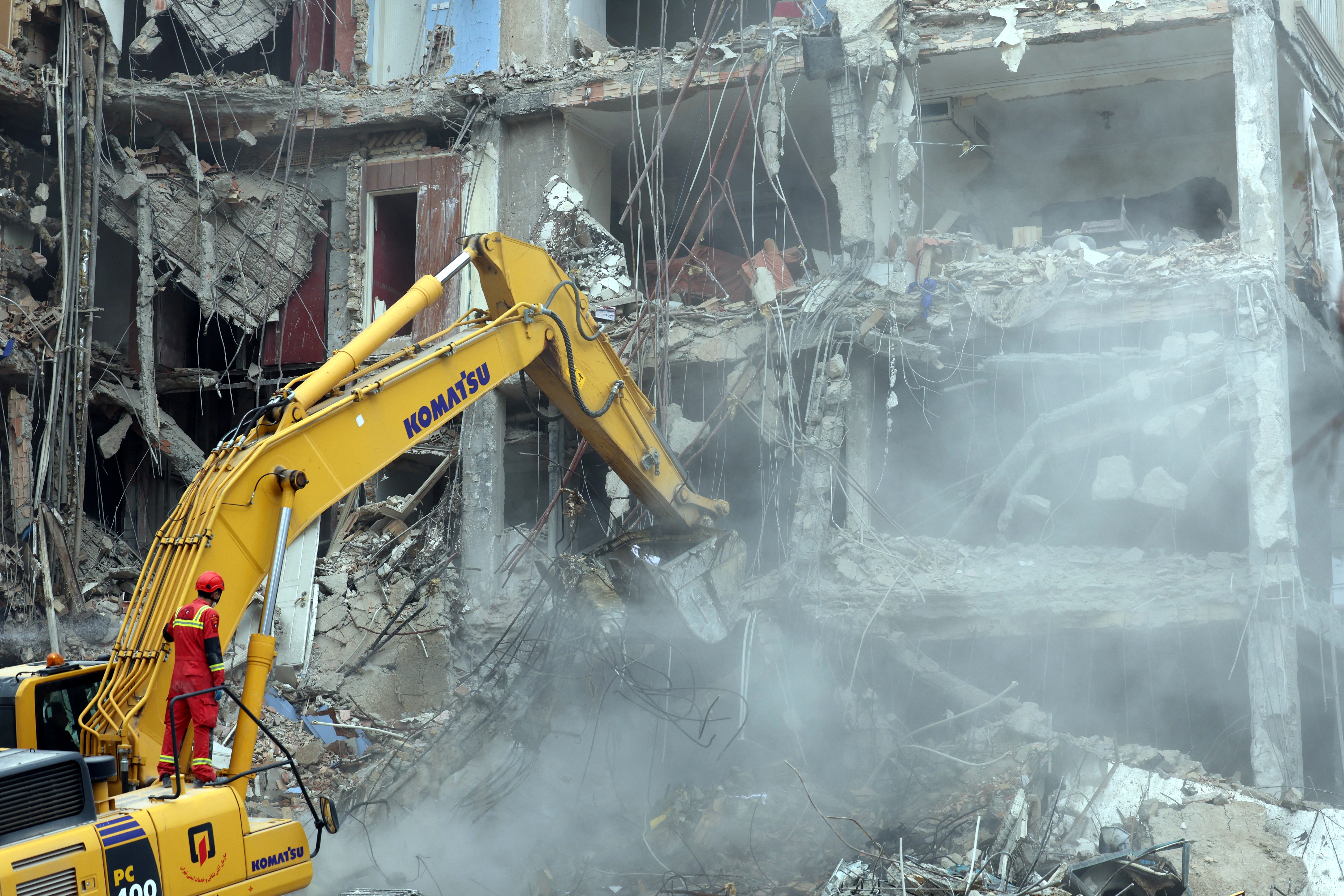 An Iranian firefighter stands on an excavator as it clears the rubble from a destroyed residential building in northern Tehran on March 23, 2026. Photo / AFP