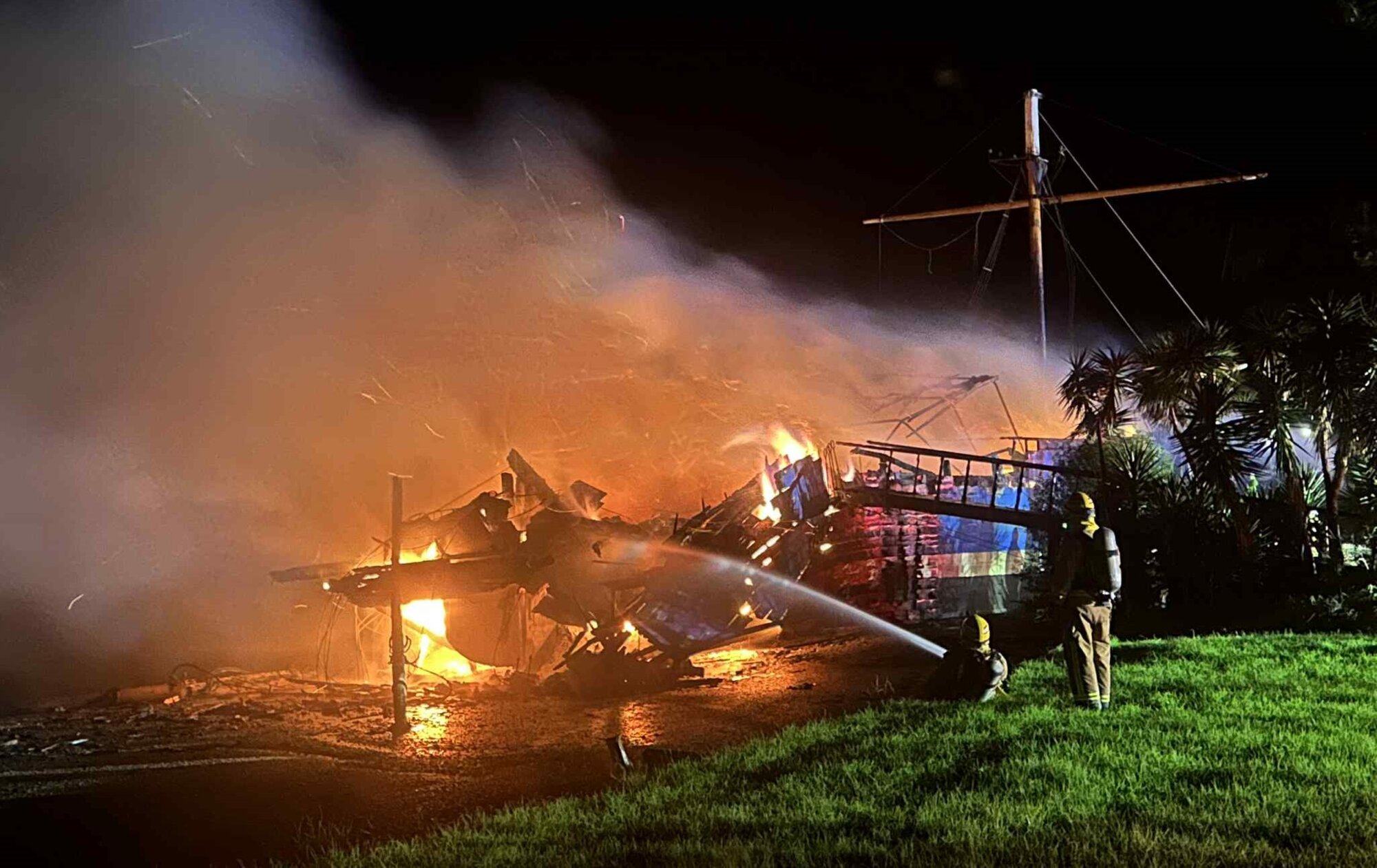 Firefighters work to extinguish a blaze on a historic ship The Tui by the Waitangi Bridge. Photo / Derek Gerritsen