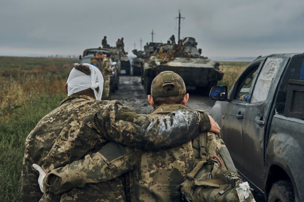 A Ukrainian soldier helps a wounded fellow soldier on the road in the freed territory in the Kharkiv region, Ukraine, in September 2022. Photo / AP file