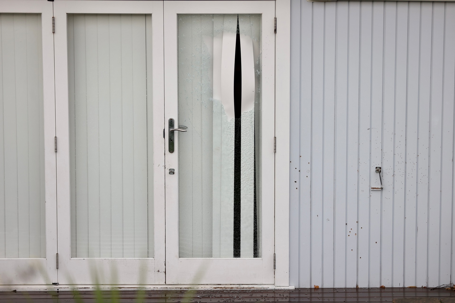 A Boundary Rd home's front doors are smashed and shotgun pellets visible in timber cladding. Photo / George Heard