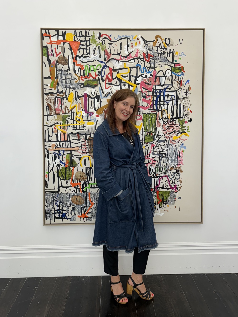 Melanie Roger at her gallery in front of a Martin Poppelwell painting.