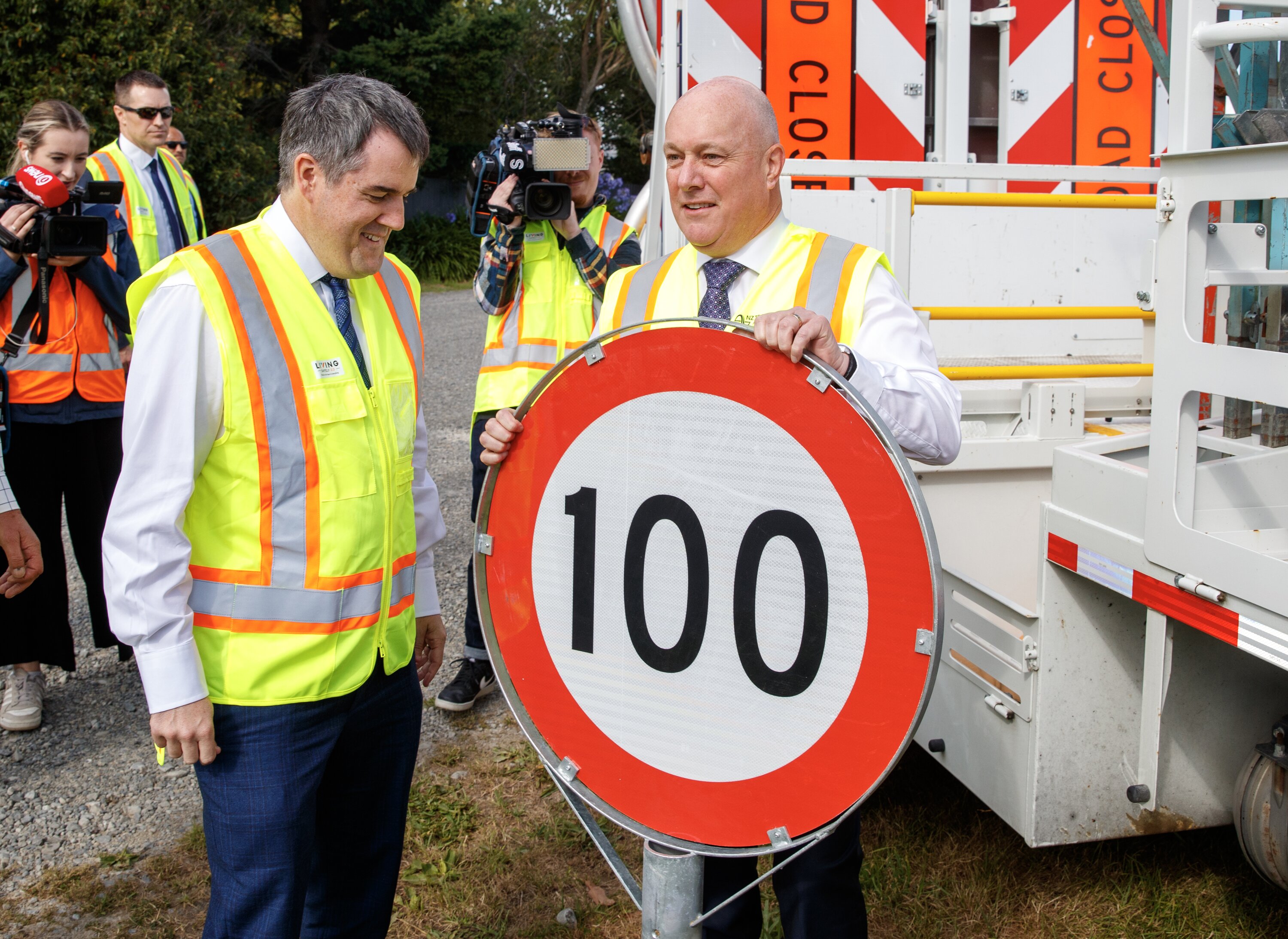 Prime Minister Christopher Luxon and Transport Minister Chris Bishop with a 100km/h road sign in Wairarapa. Photo / Mark Mitchell








