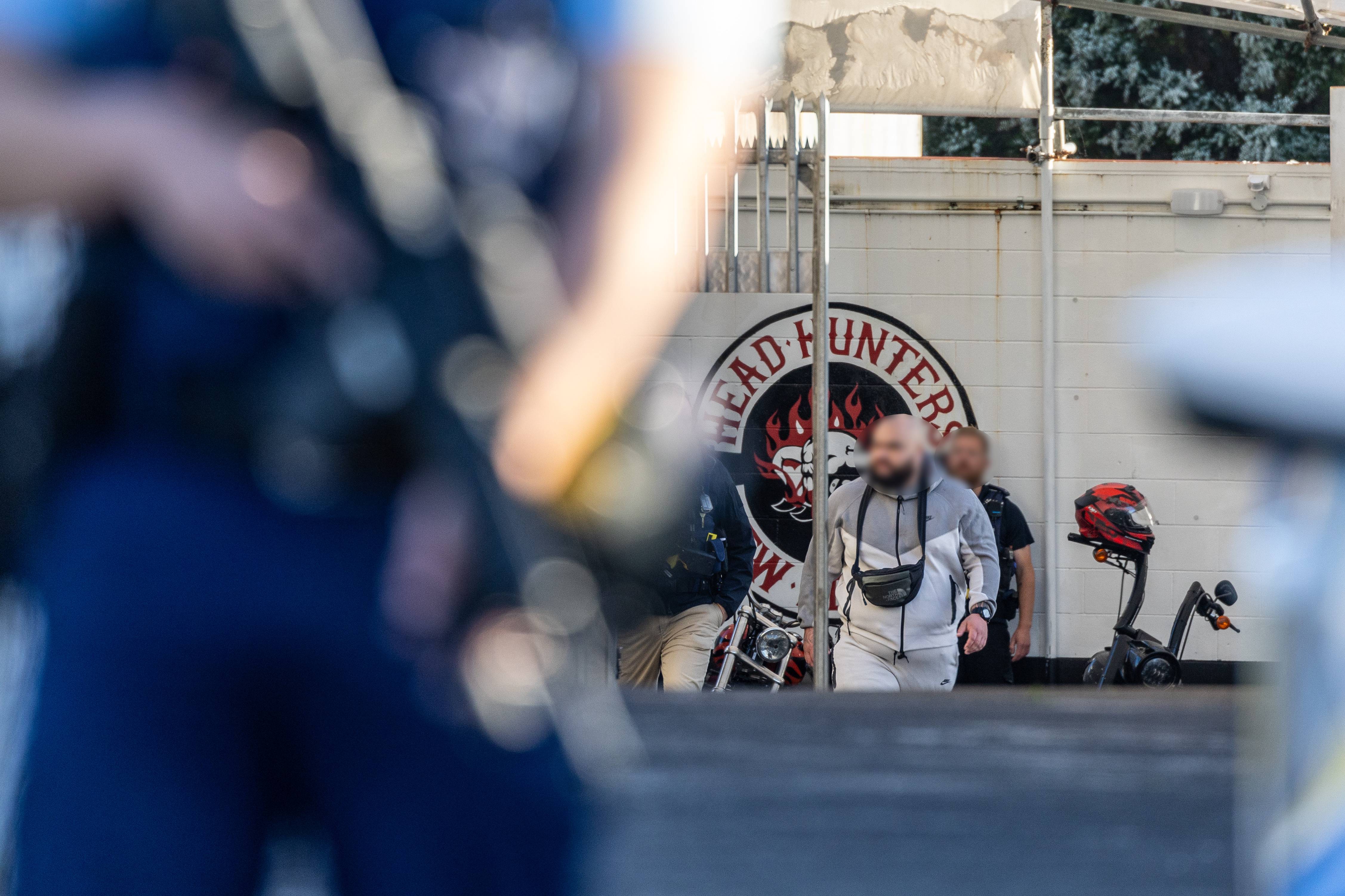 Gang members were led out of a gang pad in Henderson, Auckland, this morning during a raid. Photo / Michael Craig
