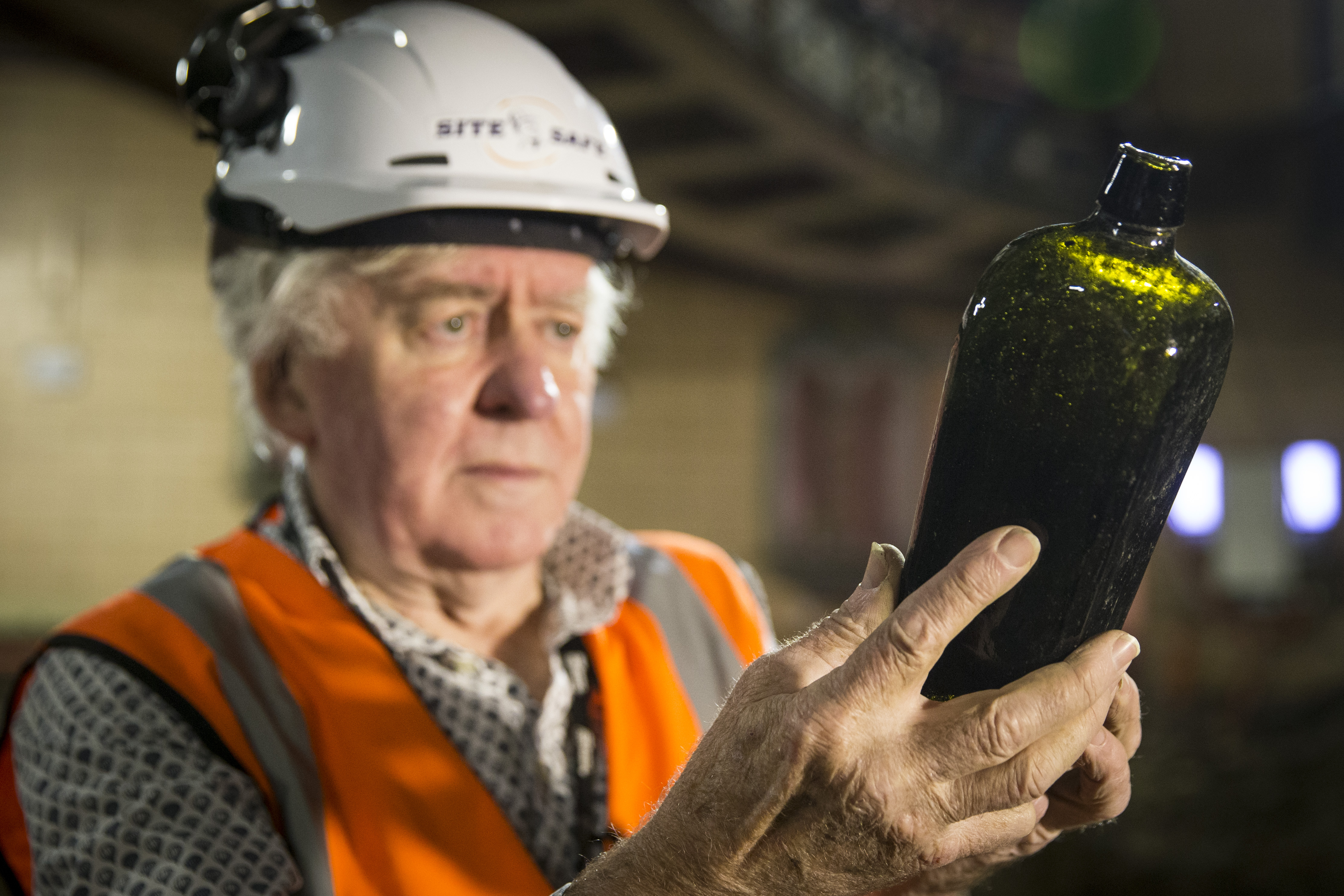 George Farrant studies an old bottle discovered in the ground underneath the St James Theatre. Photo / Jason Oxenham