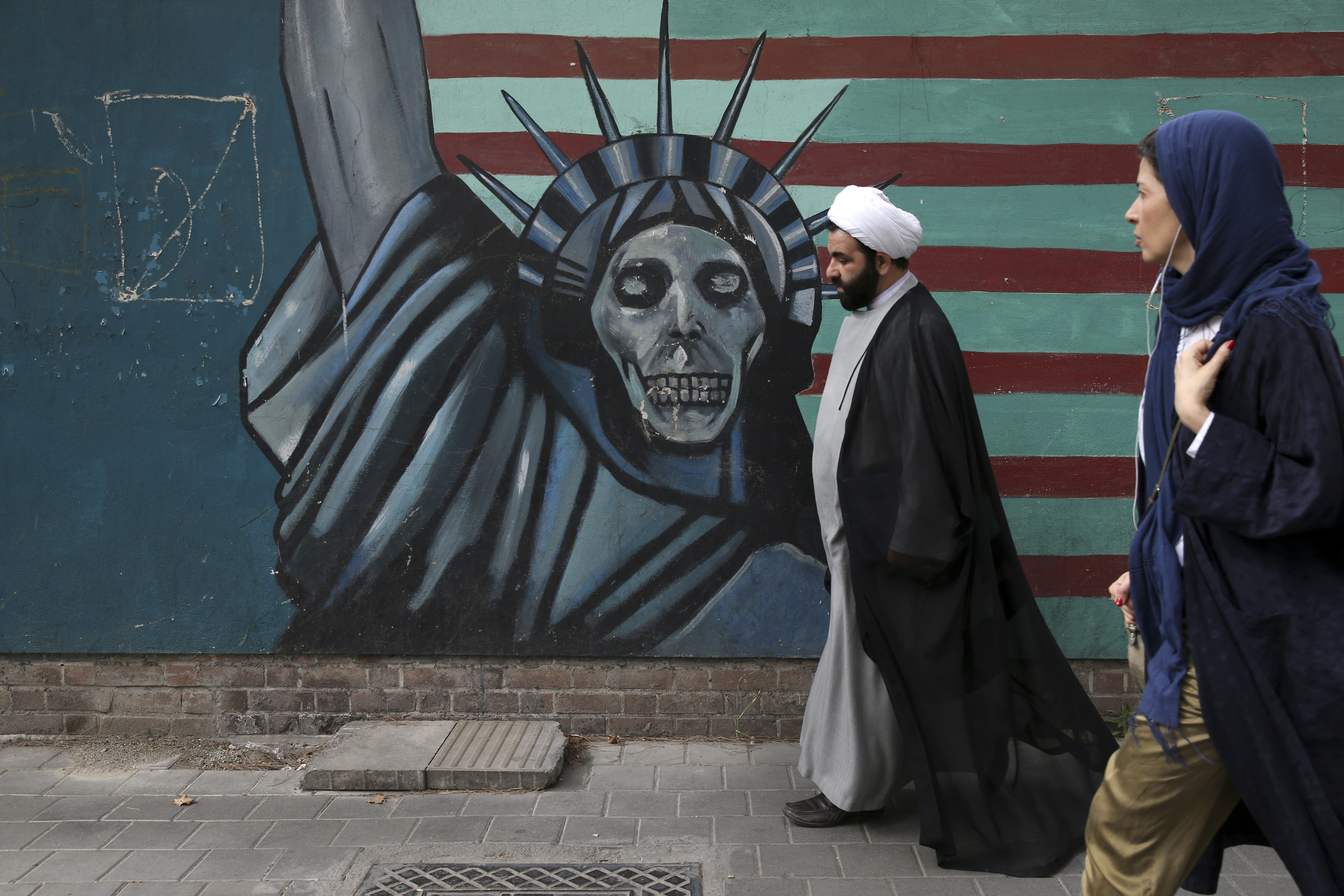 A cleric and a woman walk past an anti-US mural painted on the wall of the former US Embassy in Tehran, Iran. Photo / AP