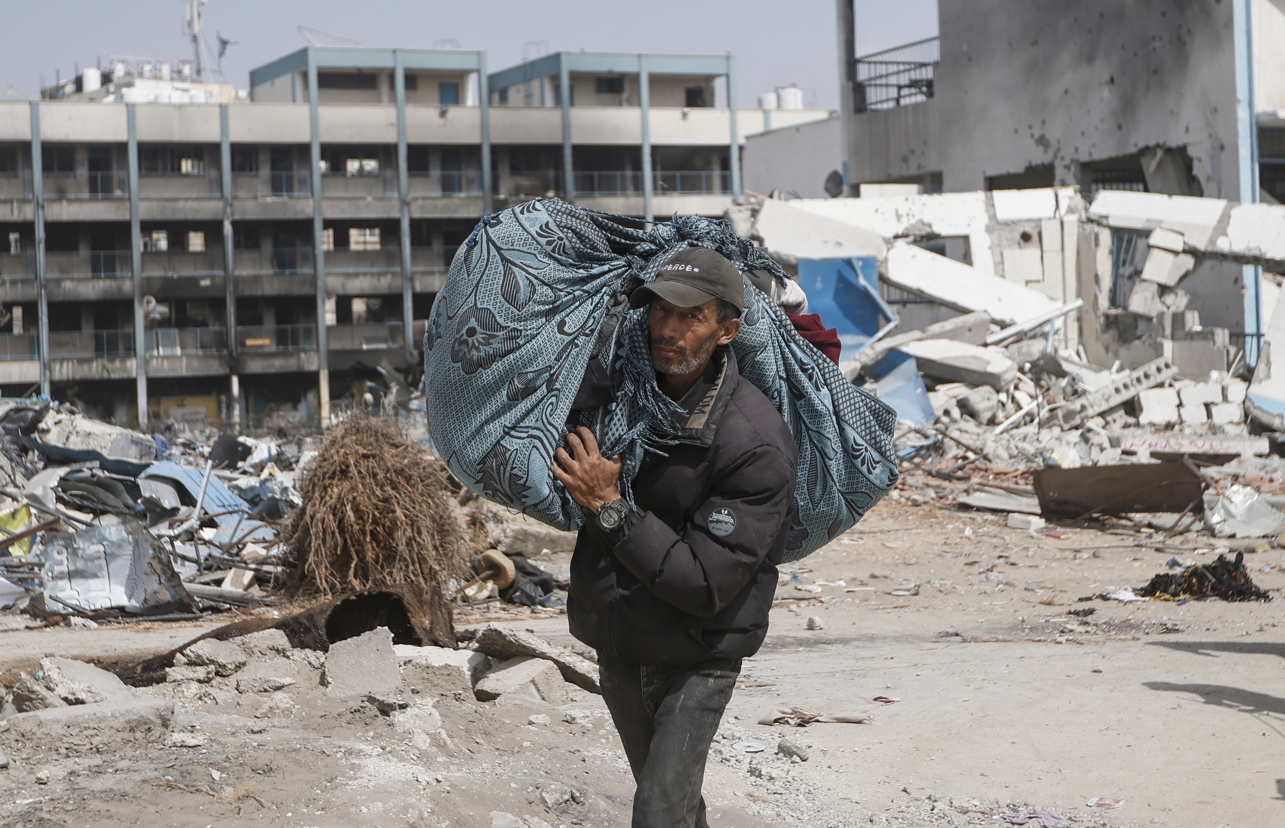 A Palestinian carries their belongings after visiting their home, destroyed in the Israeli offensive on Khan Younis, Gaza Strip. Photo / AP