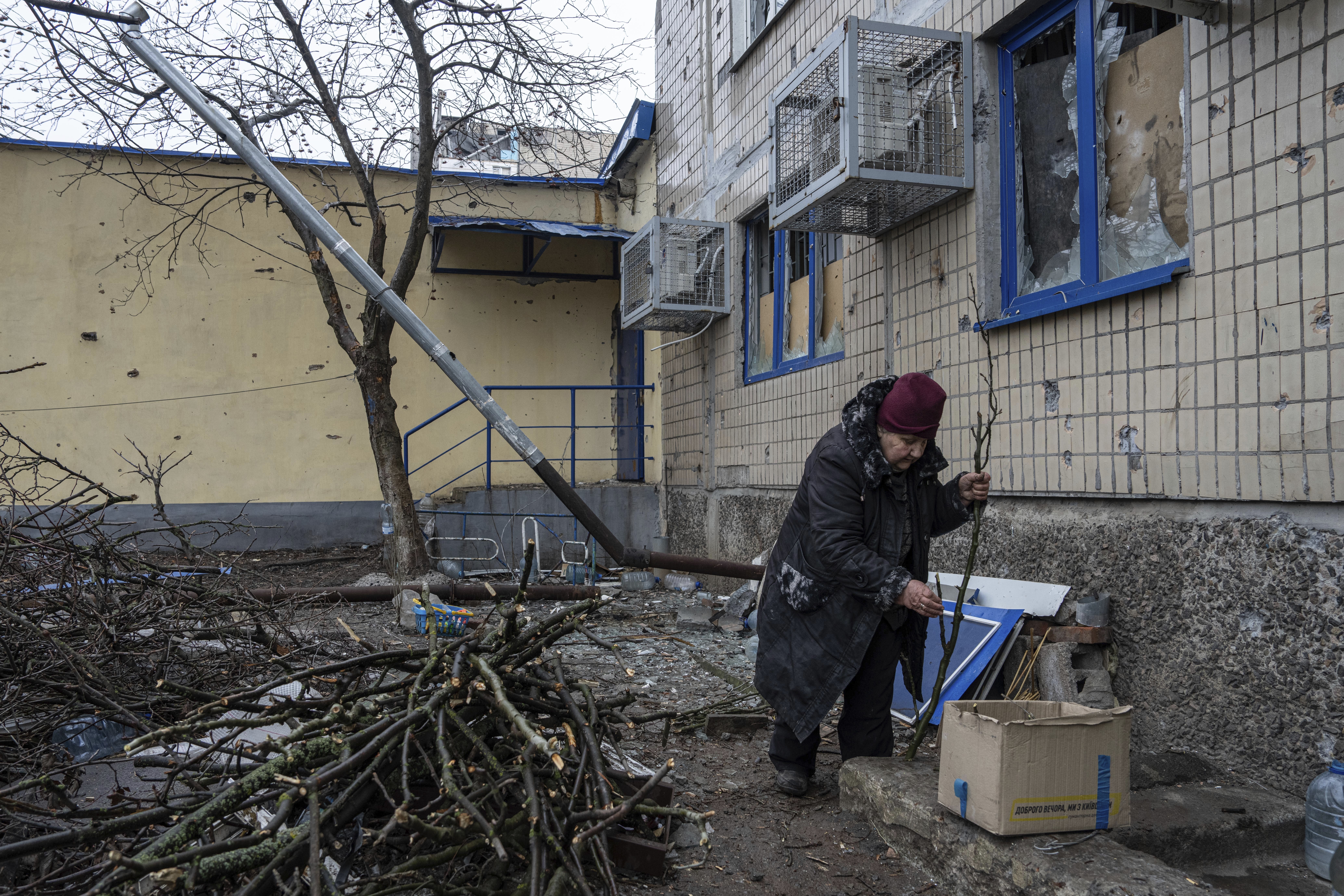 A resident breaks dead tree branches to heat her basement in the frontline city of Vuhledar, Ukraine. Photo / AP