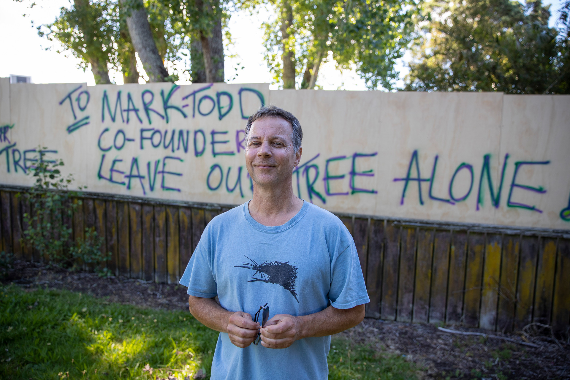Wayne Dwopsnic chained himself to the crane to stop it from felling a locally-protected macrocarpa tree. Photo / Michael Craig