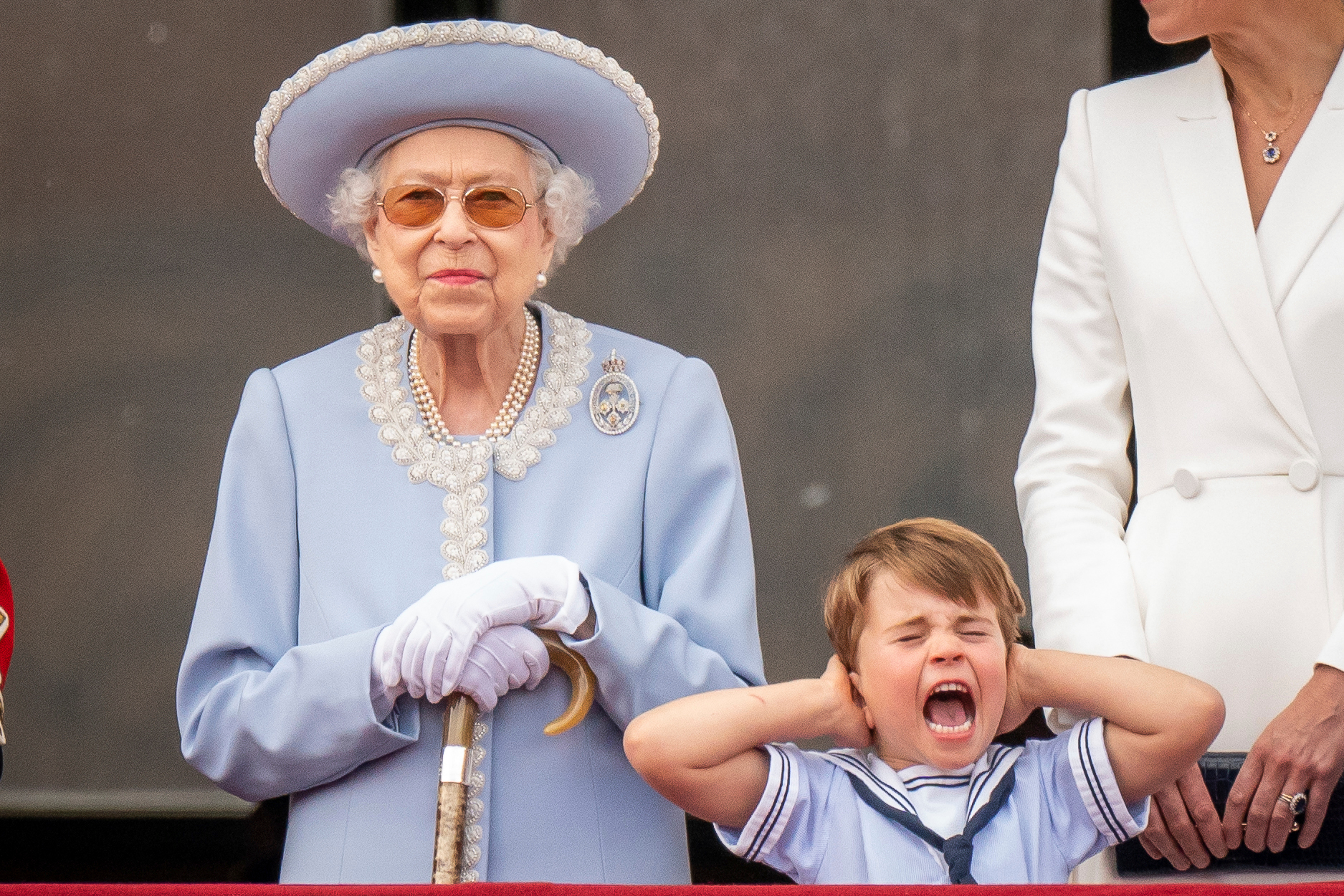 Queen Elizabeth II stands as Prince Louis covers his ears on the balcony of Buckingham Palace after the Trooping the Colour ceremony. Photo / AP