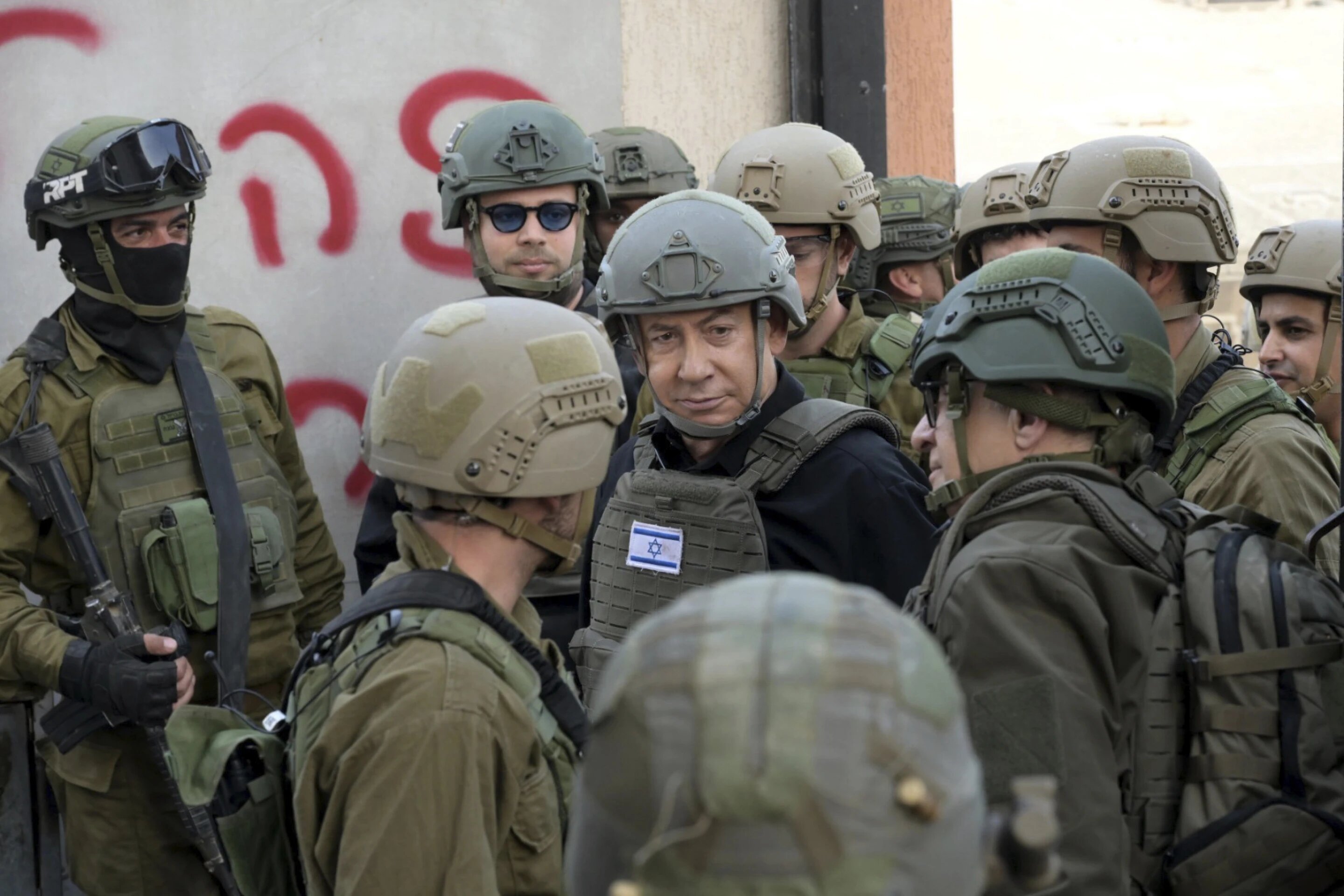Israeli Prime Minister Benjamin Netanyahu (centre) wears a protective vest and helmet as he receives a security briefing with commanders and soldiers in the northern Gaza Strip. Photo / AP
