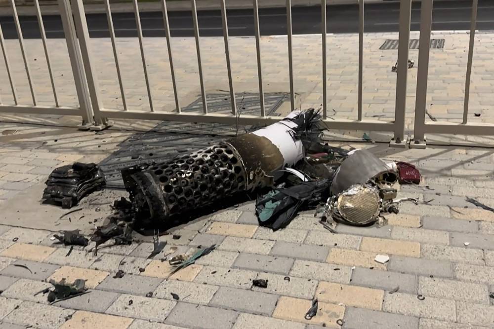 This frame grab take from AFPTV footage shows the remnants of an Iranian missile intercepted over Qatar, as it lies on a pavement near a fence on June 23, 2025. Qatar said on June 23, the security situation was 