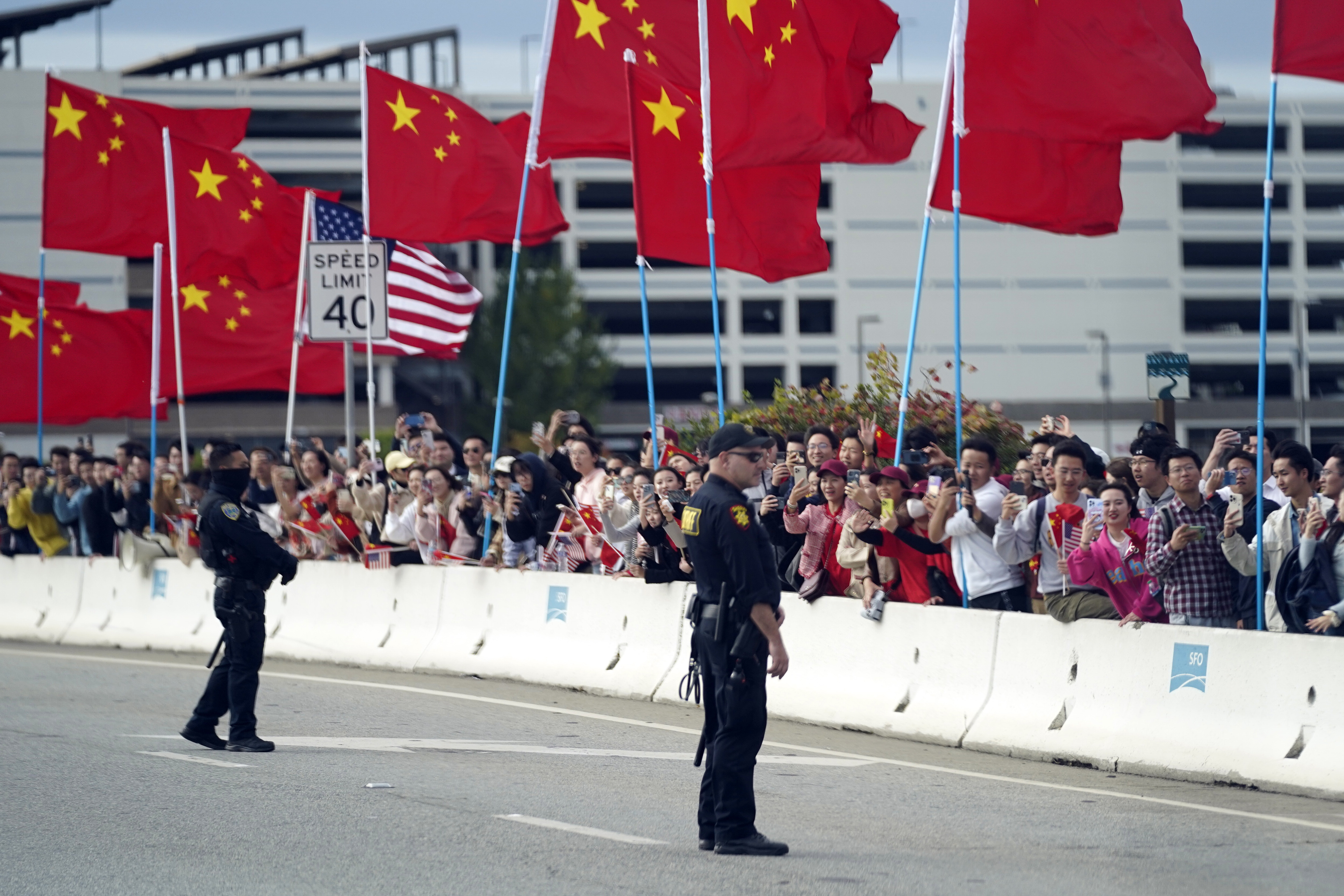 With American and Chinese flags flying, people watch as the motorcade carrying US President Joe Biden drives past on Tuesday, November 14, 2023 in San Francisco. Photo / AP