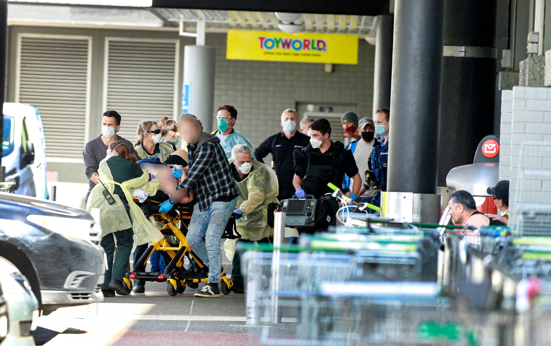 Police and paramedics at New Lynn Countdown race a stabbing victim to a waiting ambulance. Photo / Alex Burton