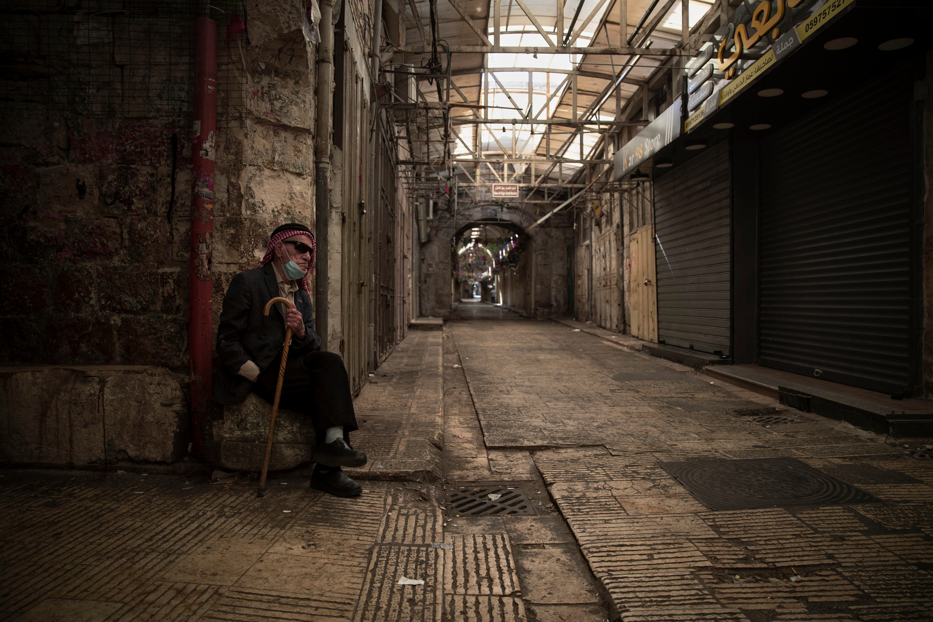 A Palestinian man sits in front of closed shops during a general strike, in the West Bank city of Nablus. Photo / AP