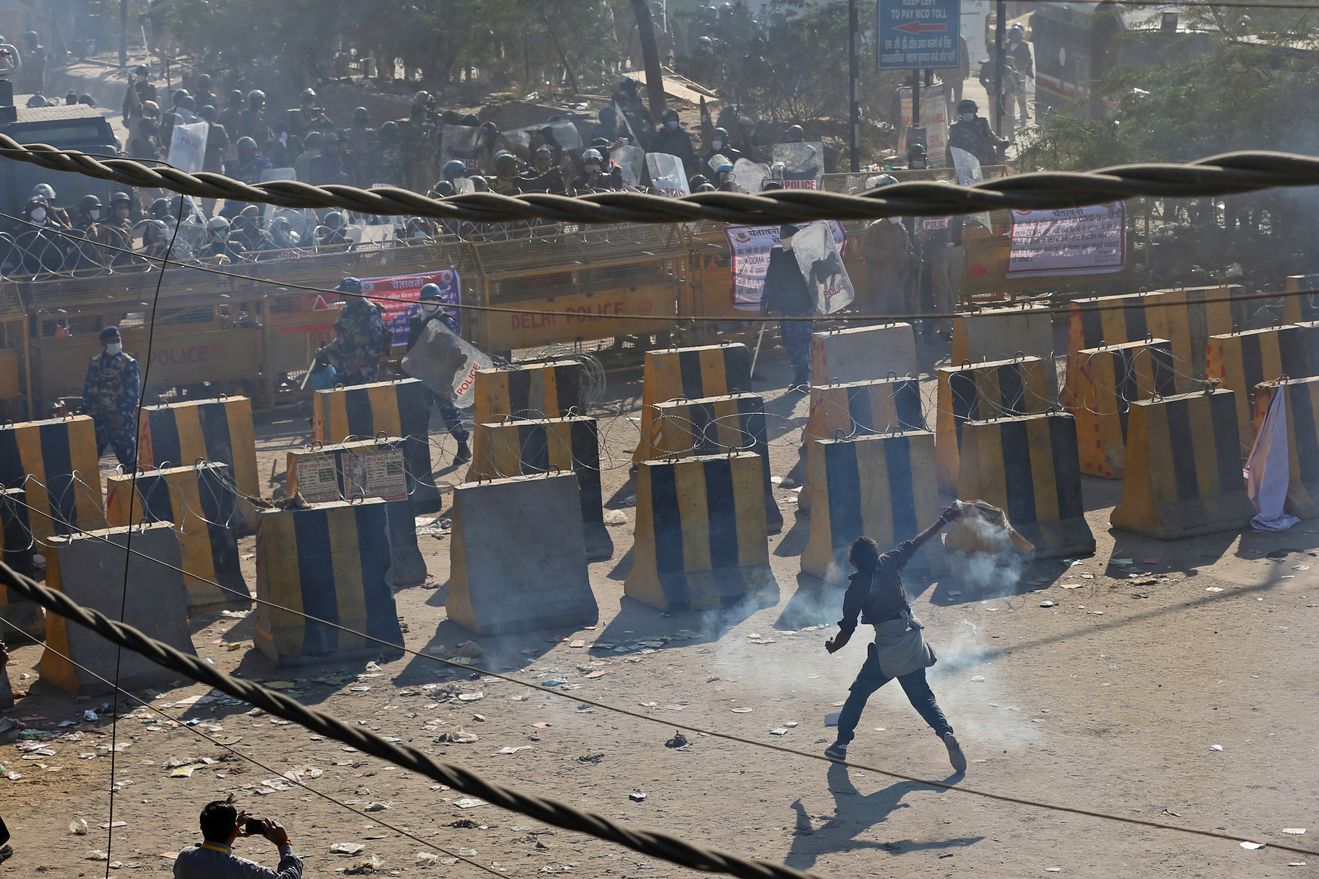 A protesting farmer throws back a tear gas shells past concrete road blocks set up by policemen, at the border between Delhi and Haryana state. Photo / AP