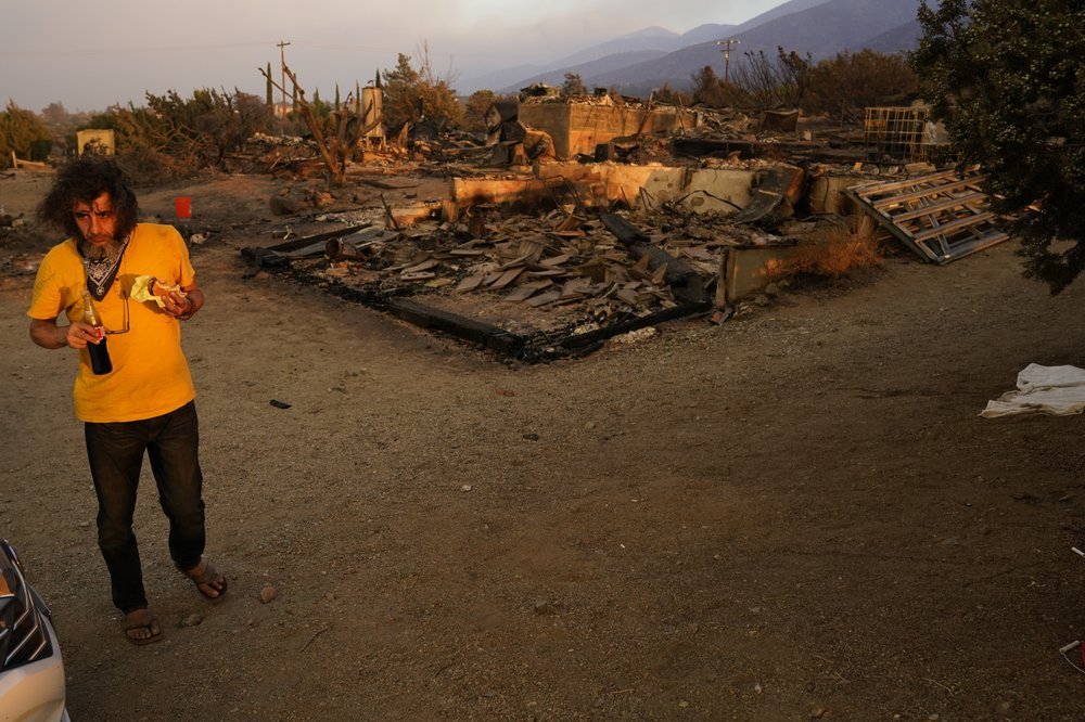 A homeowner, wishing not to be identified, stands in front of his fire-ravaged home Saturday. Photo / AP