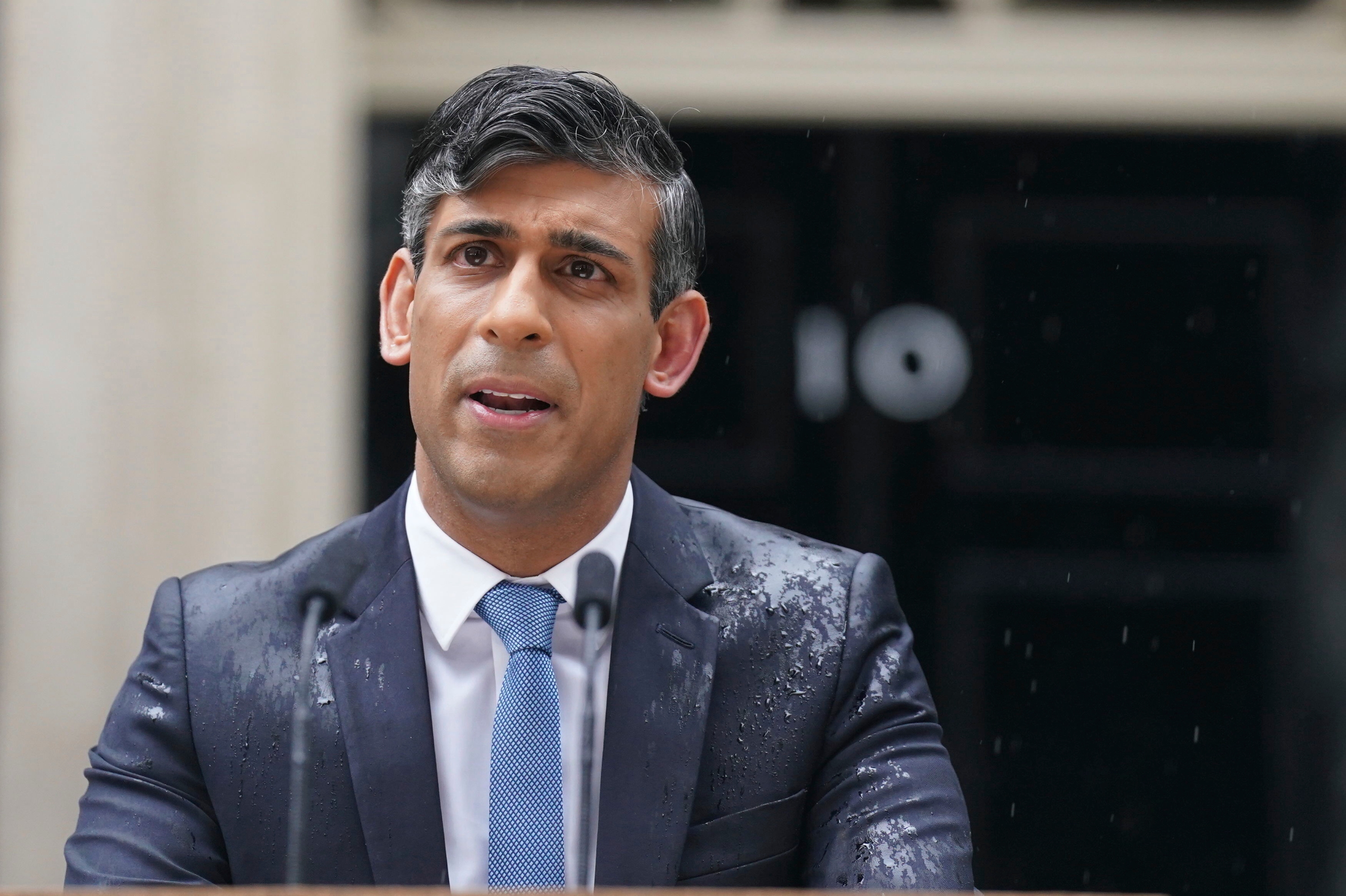 Rishi Sunak is seen speaking to the media, as heavy rain falls, outside 10 Downing St in London as he announces that he is to call a general election for July 4. Photo / AP