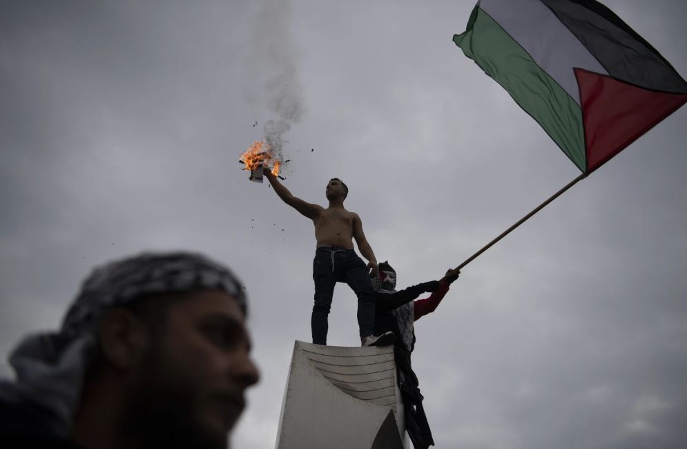 A man holds a burning Israeli flag, while another waves a Palestinian one, during a protest in front of the Israeli Embassy in Athens, Greece. Photo / AP