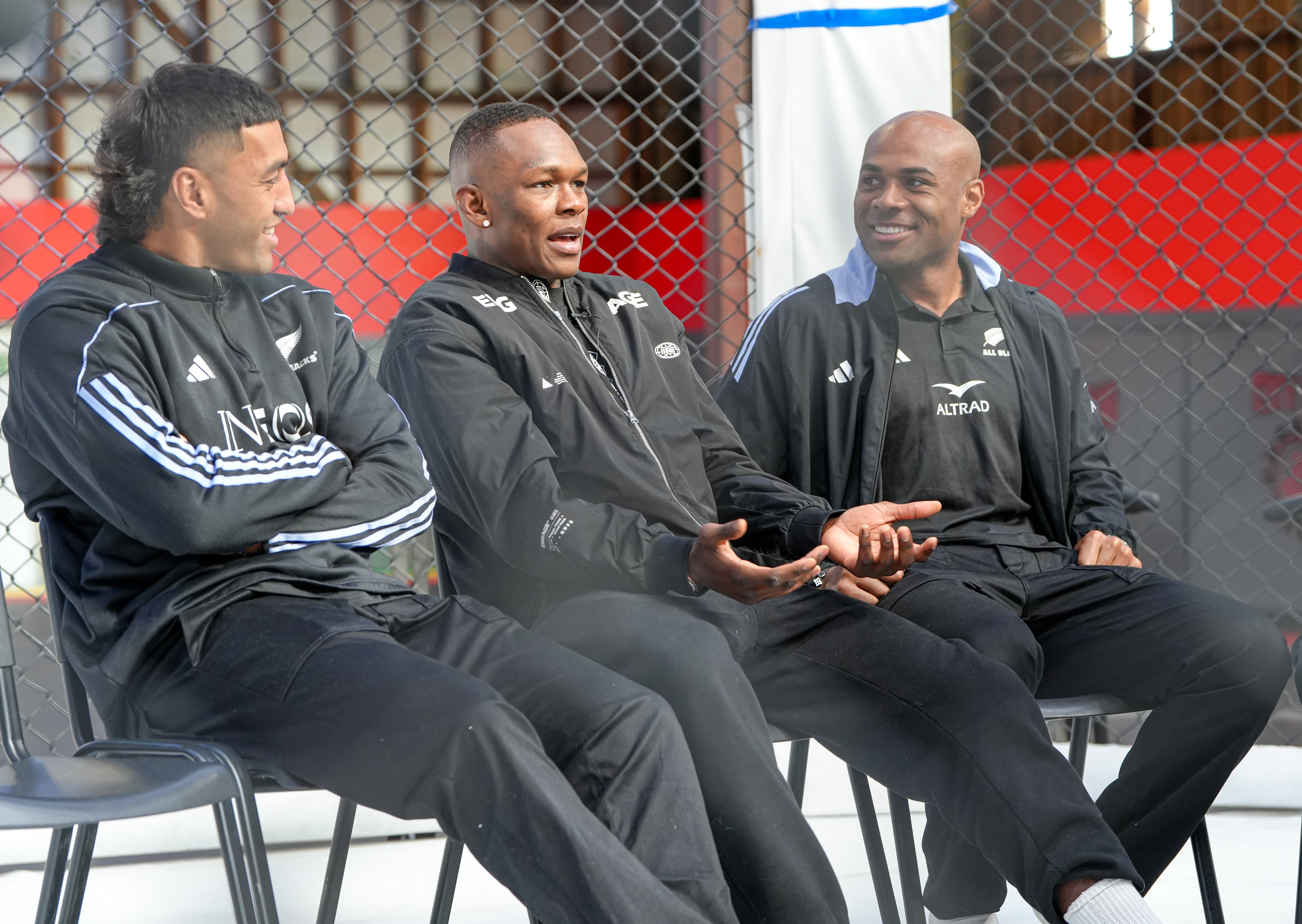 Israel Adesanya (centre) speaks with All Blacks Rieko Ioane (left) and Mark Tele'a. Photo / Alyse Wright