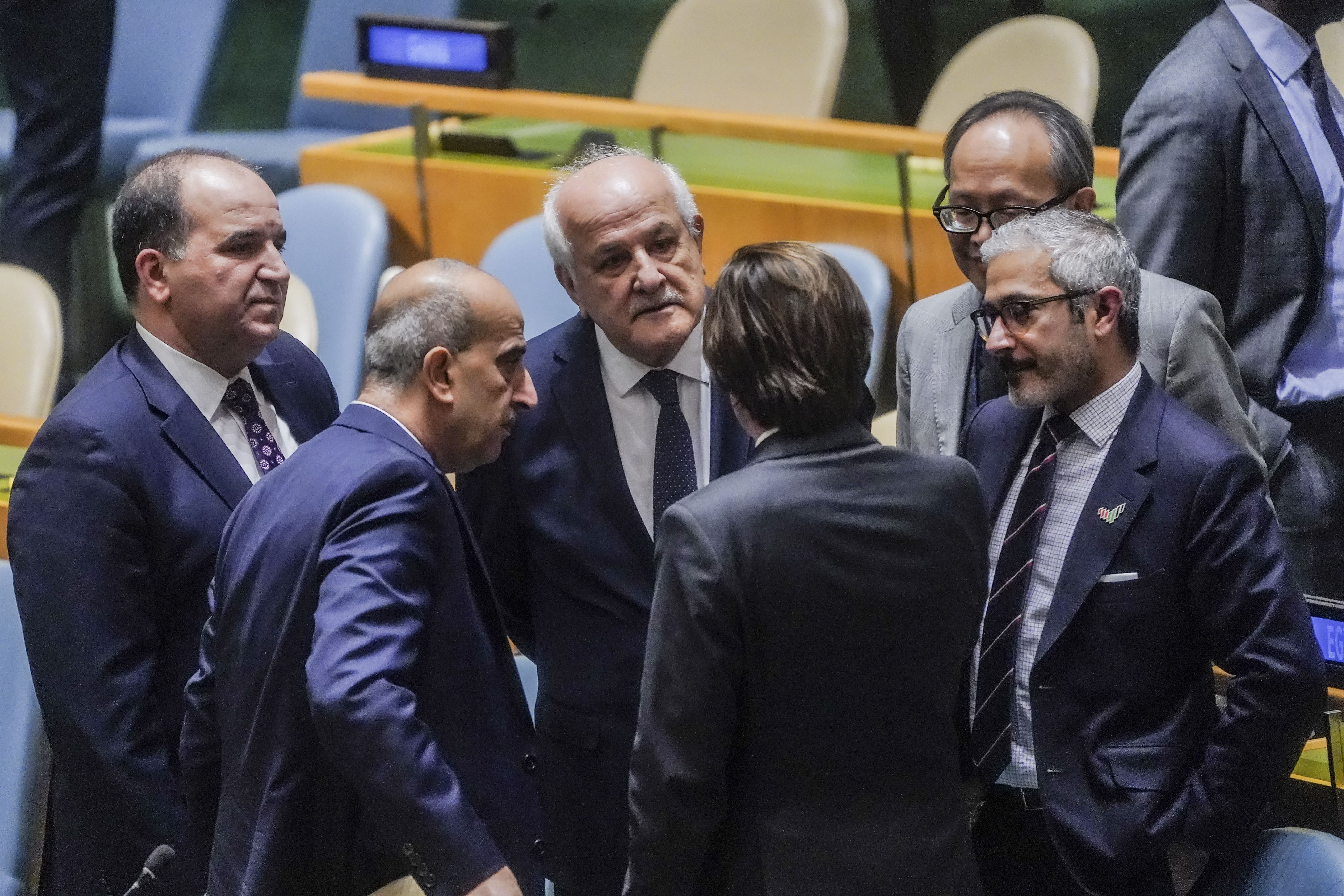 Palestinian United Nations Ambassador Riyad Mansour (third from left), confers with diplomats before the United Nations General Assembly vote on a resolution, calling on Israel to uphold legal and humanitarian obligations in its war with Hamas. Photo / AP