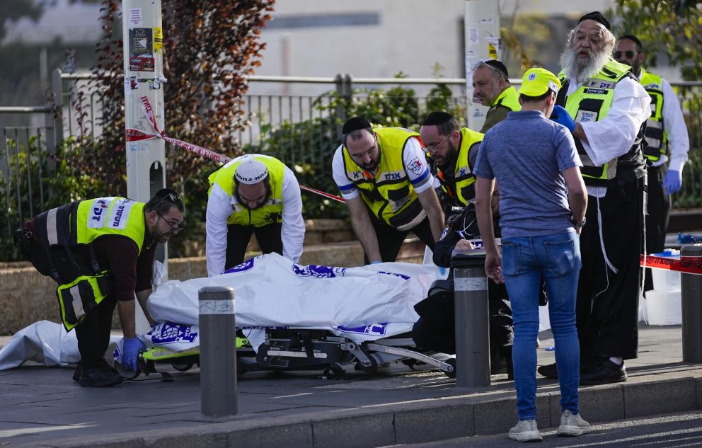 Volunteers from the Zaka rescue service remove a body killed in the shooting attack in Jerusalem. Photo / AP
